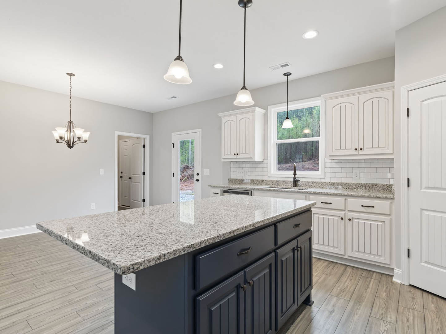 Marble kitchen island with waterfall edge, white cabinetry, stainless steel appliances, pendant chandelier, and black hardware on doors and drawers