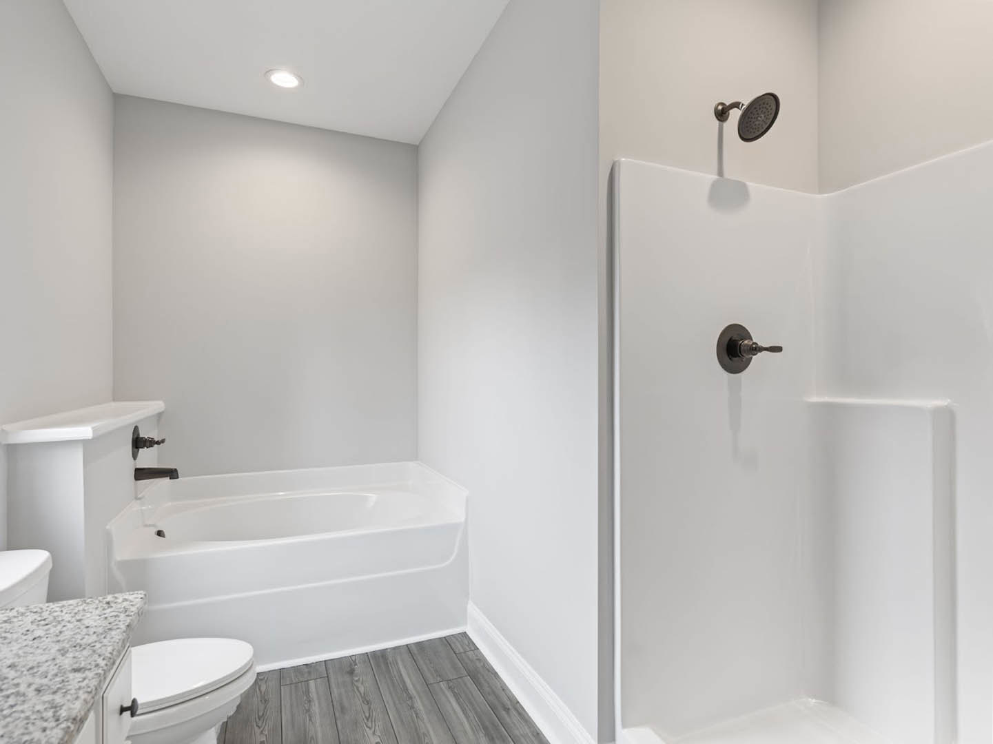 Modern bathroom featuring a freestanding white bathtub, glass-enclosed shower with tile walls, quartz countertop vanity, chrome fixtures, and neutral finishes.