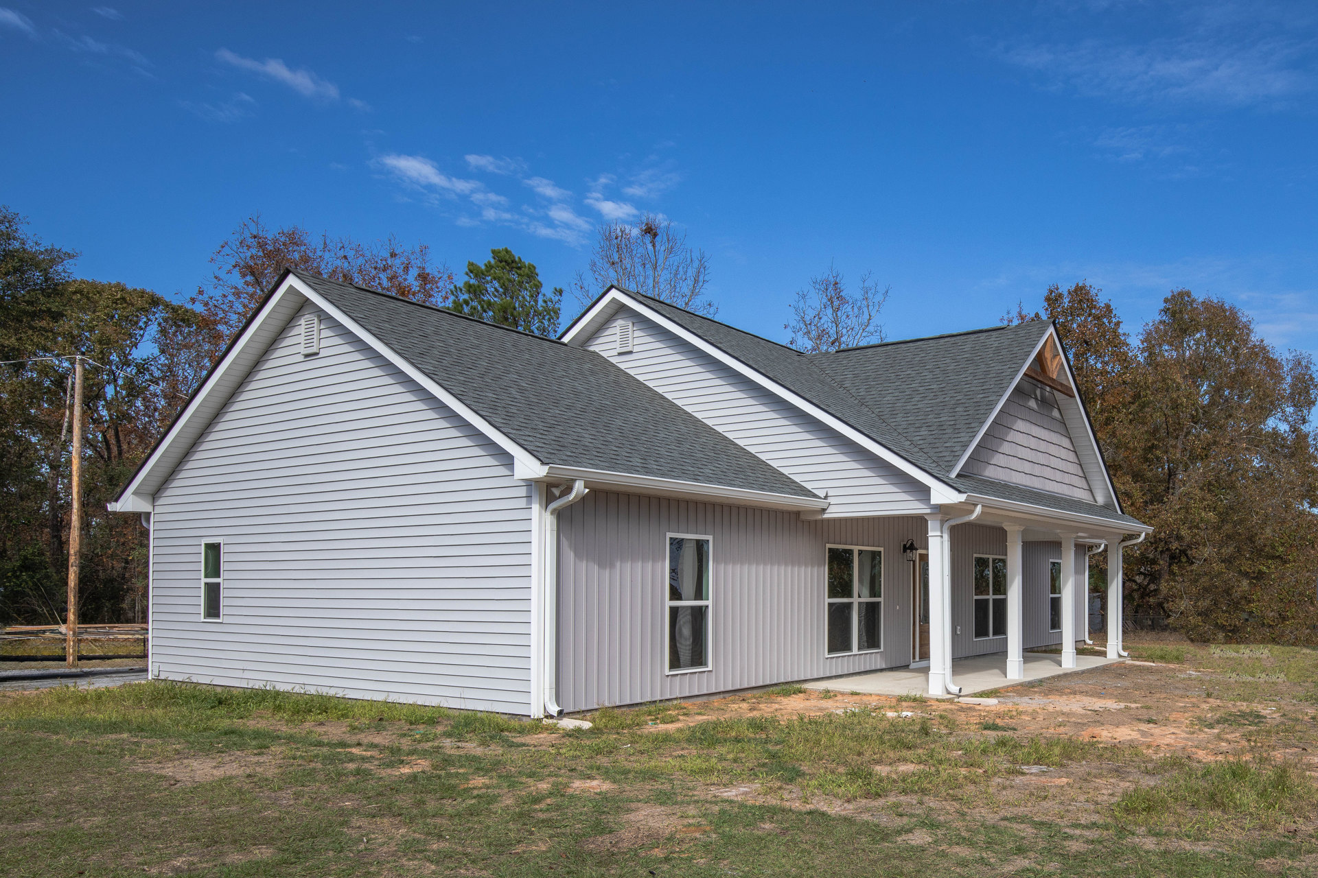Large porch with white railings, grey roof, multiple windows, mature trees, and Robert Frost Farm visible in the background