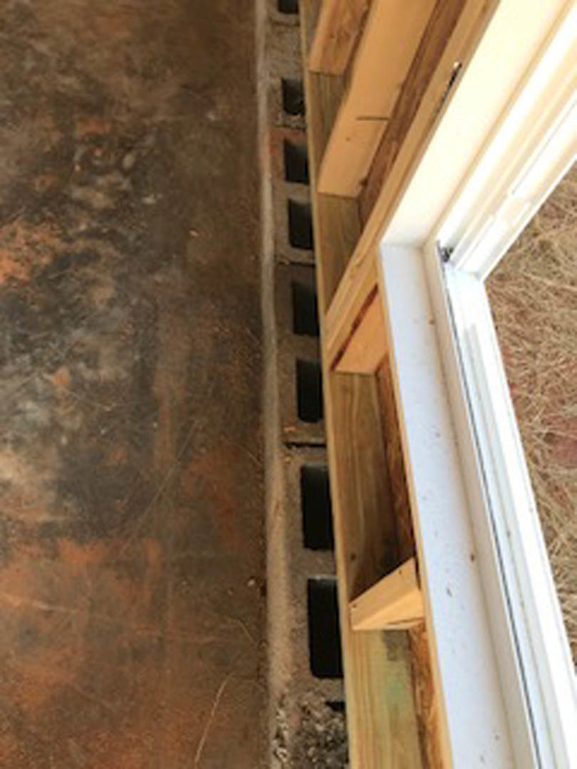 Wood window frame with deep sill set above smooth concrete floor in residential interior
