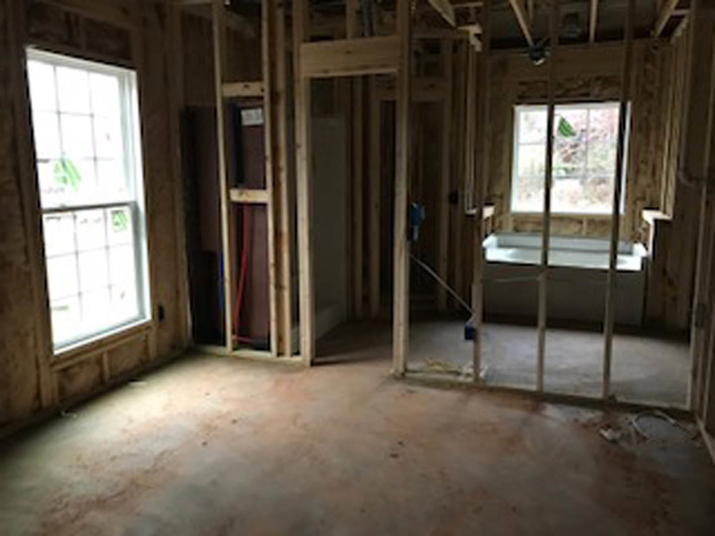 Concrete floor with wood trim, single window framed by calendars, stainless steel sink, partial view of a person's hand in foreground