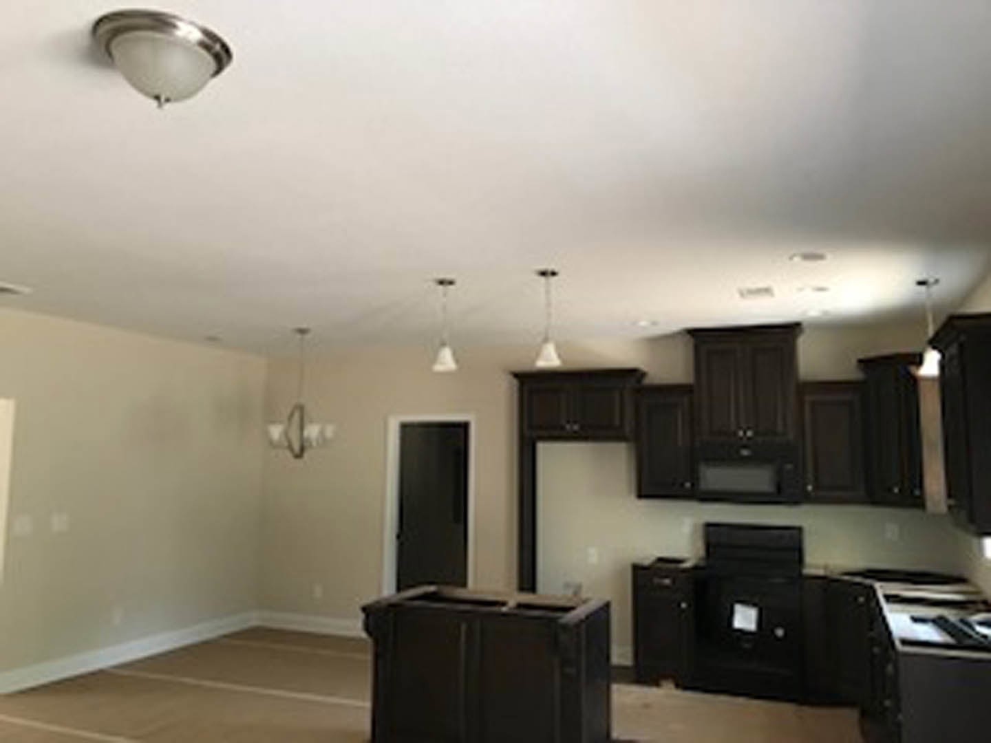 Kitchen with dark wood cabinets, white ceiling, light countertops, stainless steel appliances, and modern lighting fixtures