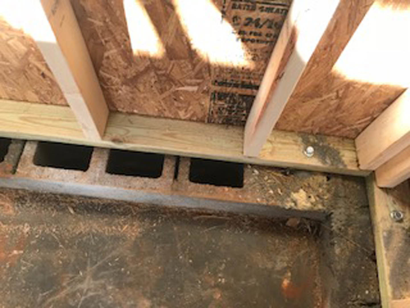 Wood-framed wall with vertical wood paneling and exposed beam, close-up of brown wood surface and partial view of wood floor with cutout