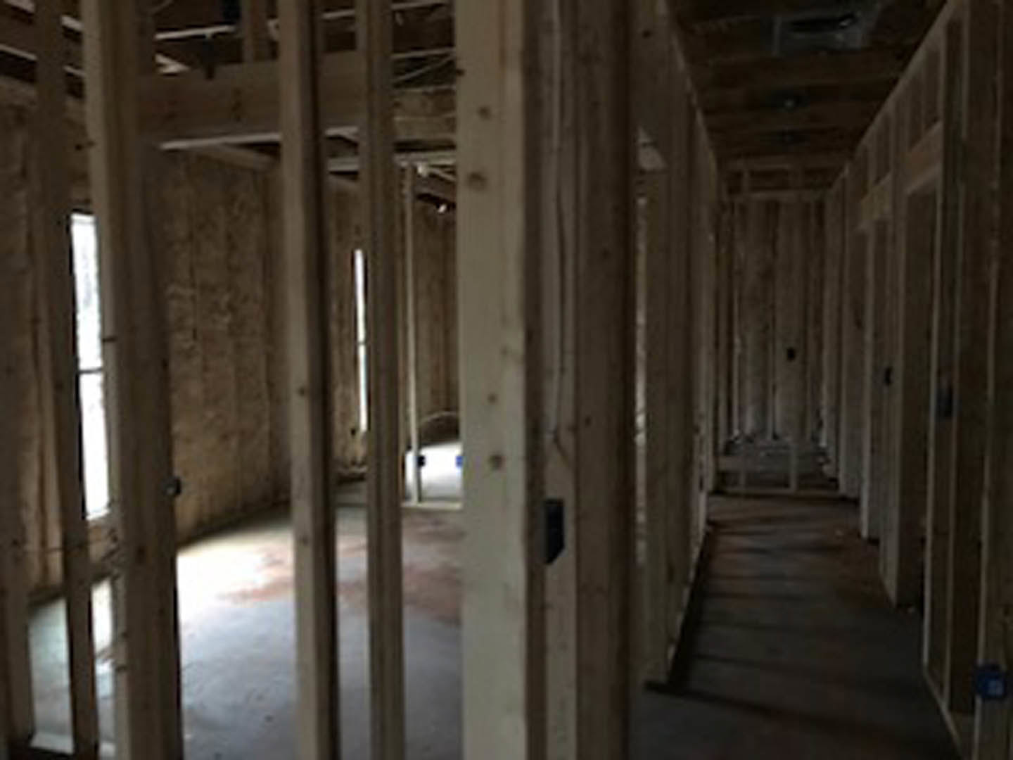 Long hallway with exposed wooden ceiling beams, light wood flooring, and neutral walls