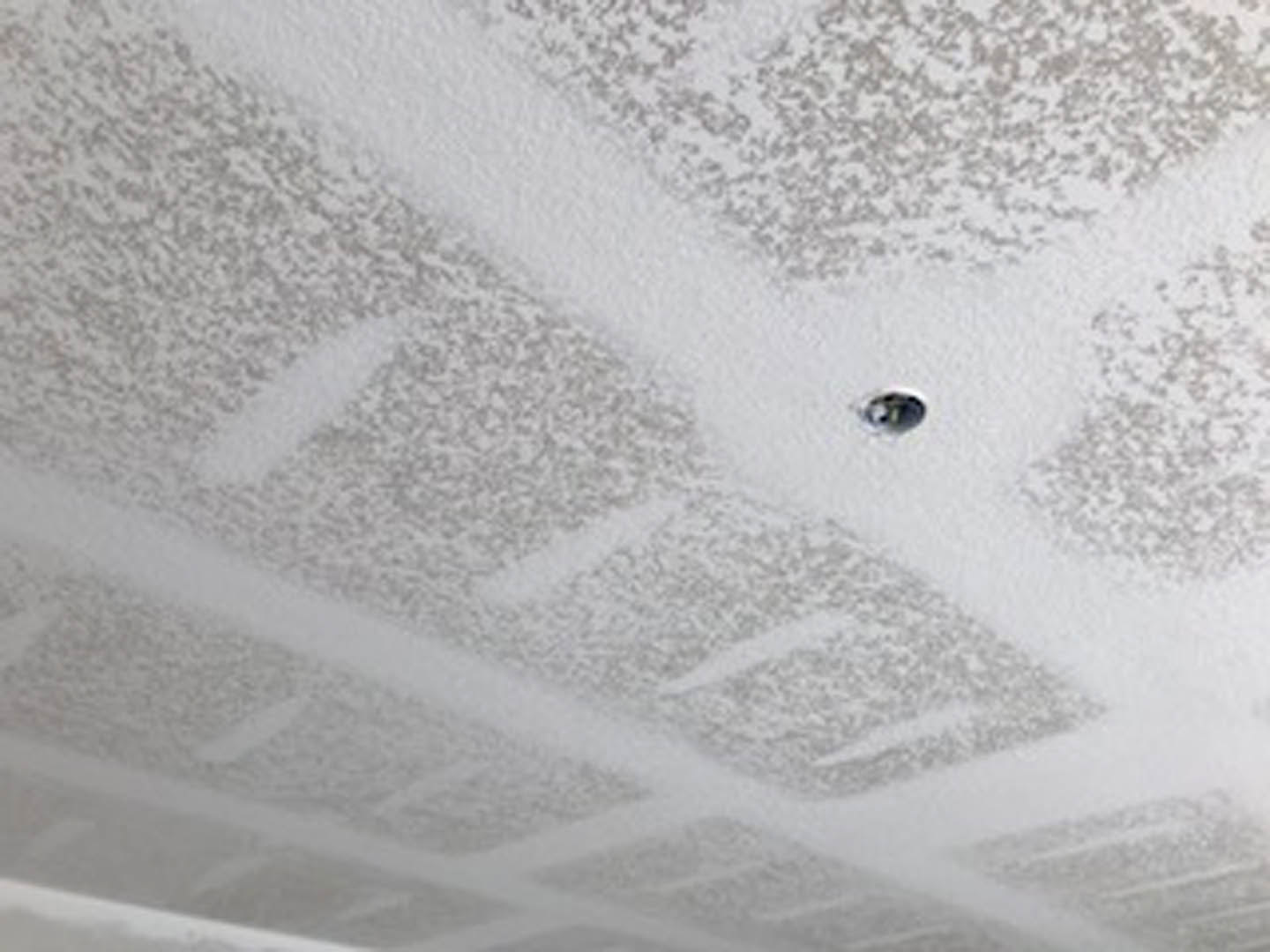 Smooth white plaster ceiling with a circular hole, surrounded by neutral walls in a modern indoor residential space
