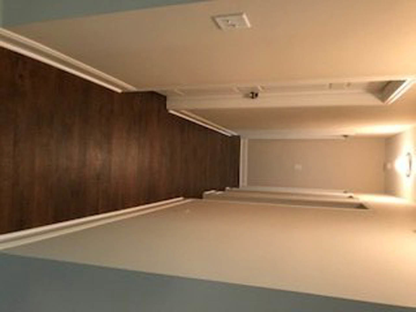 Hallway with white plaster walls, dark hardwood flooring, white baseboard trim, and ceiling molding