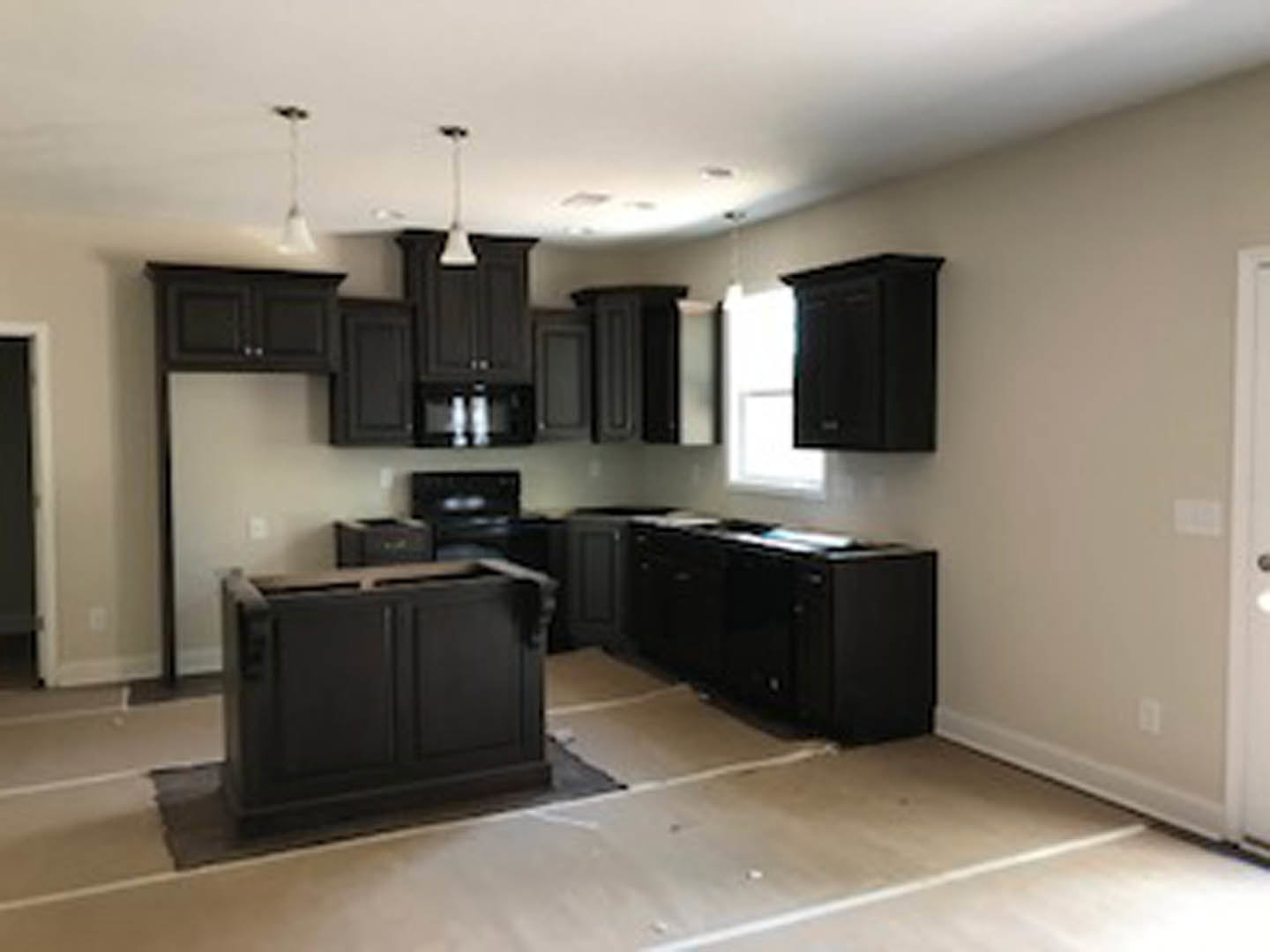 Kitchen with matte black cabinets, light wood countertops, stainless steel sink, and salt shakers on the counter