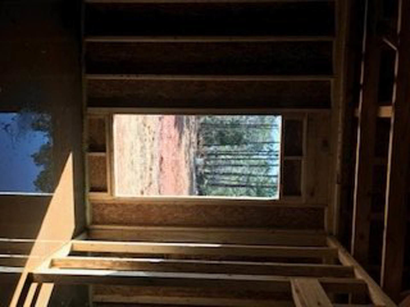Wood-framed window set in a light-colored wall with visible grain and smooth finish
