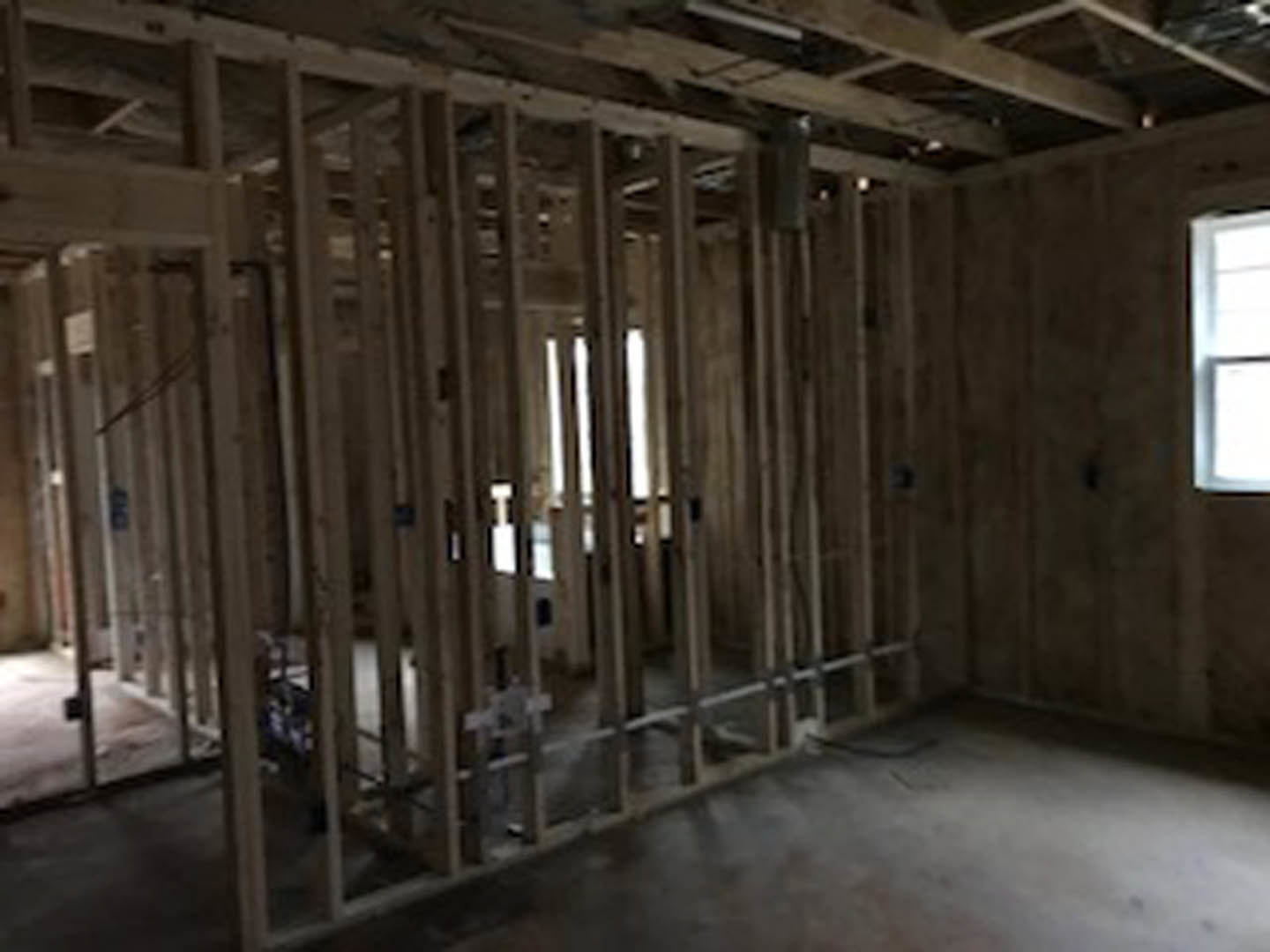 Exposed wood ceiling beams, large window with white trim, light-colored walls, and hardwood flooring in a modern interior room
