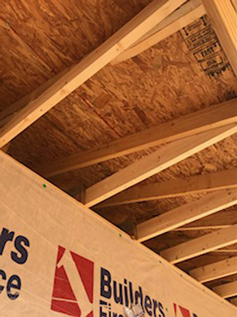 Exposed wooden beams and planks forming a tan and brown ceiling structure