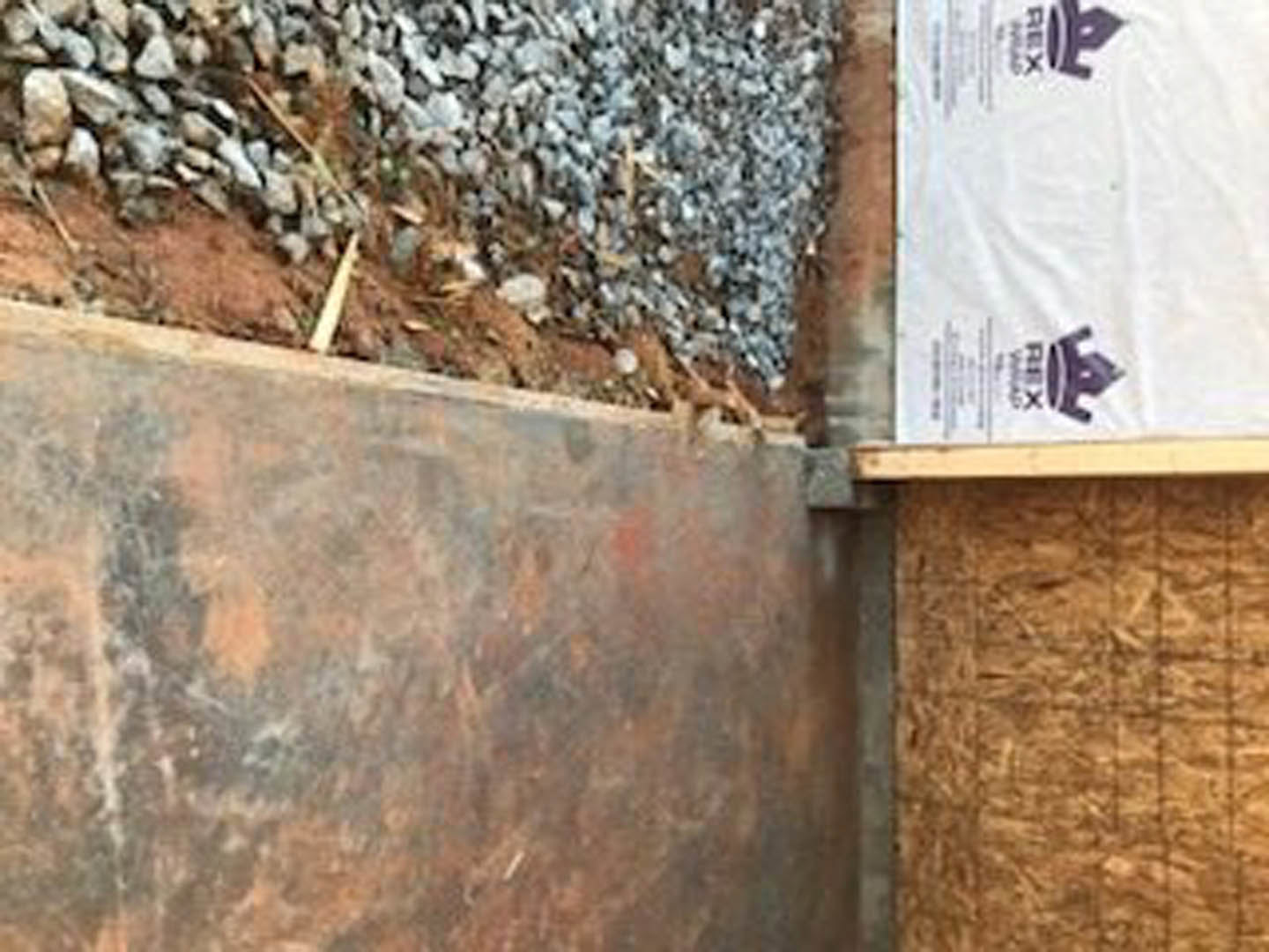 Concrete foundation topped with a white sheet, surrounded by gravel and construction materials, exterior setting