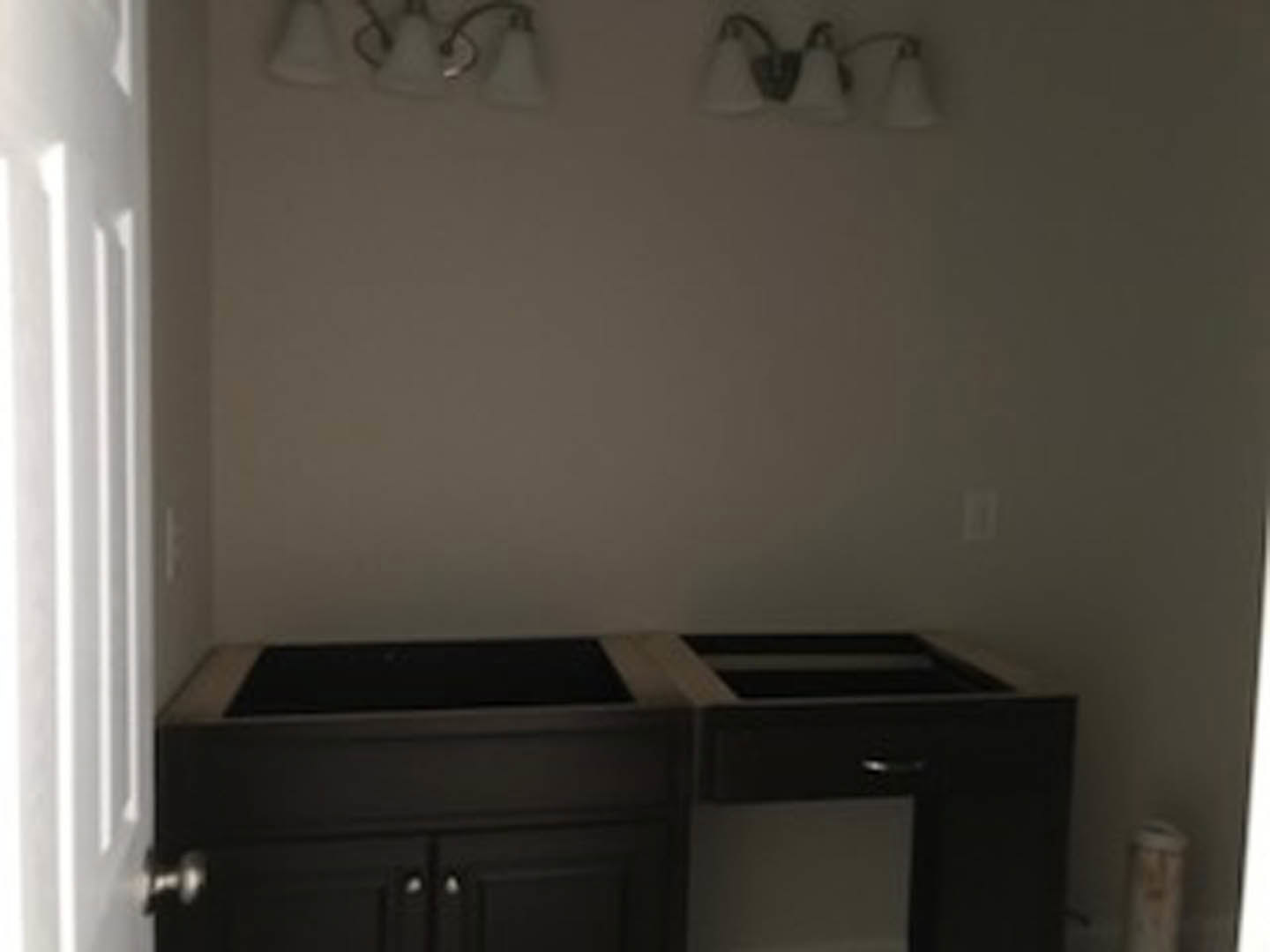 Dark wood desk with black countertop and drawers in a room, white fabric and object nearby, door visible in background