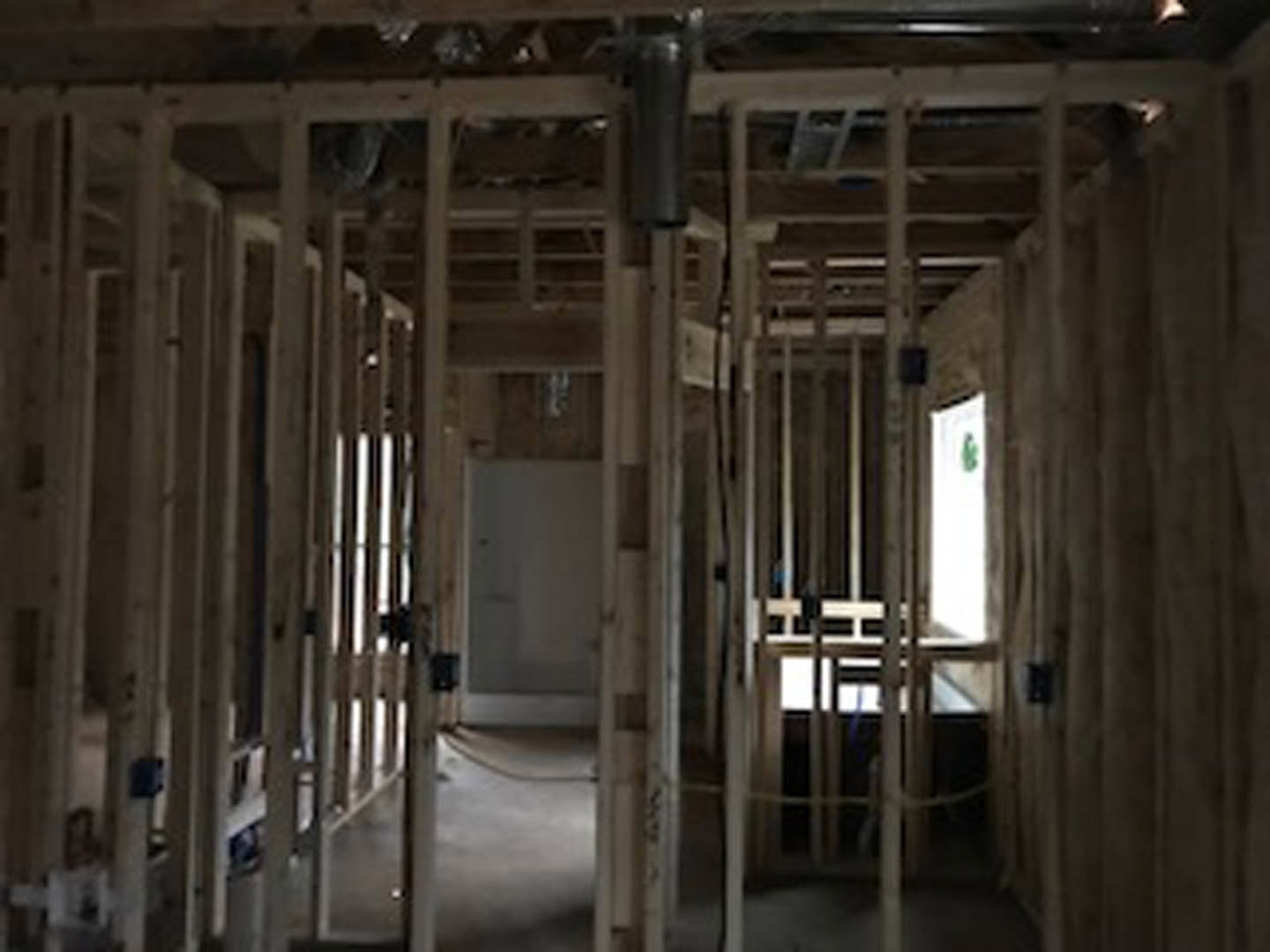 Open room with exposed wood framing, unfinished walls, visible beams, and a window; construction materials and ladder present.