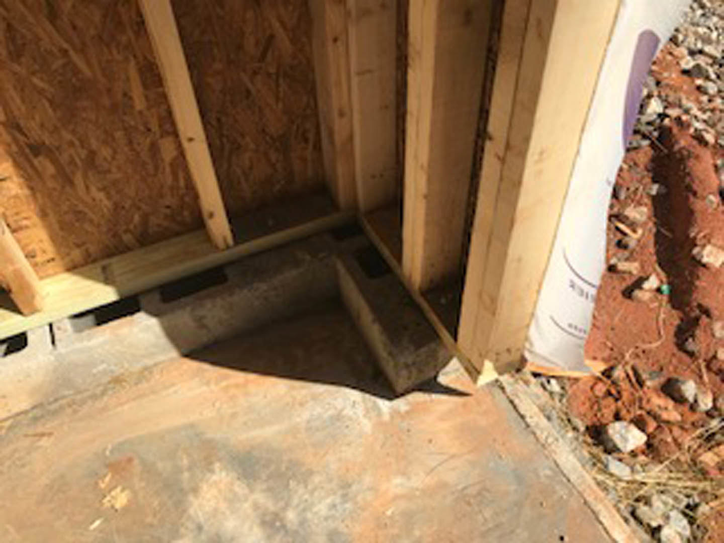 Unfinished interior with exposed lumber framing, white composite wall panels, and construction materials on the ground