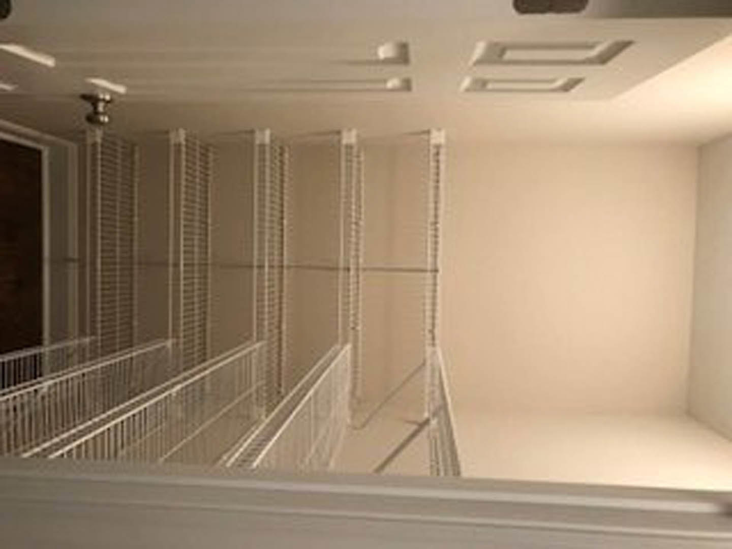 White-painted hallway with smooth plaster walls, white door, white ceiling, and staircase featuring a white railing