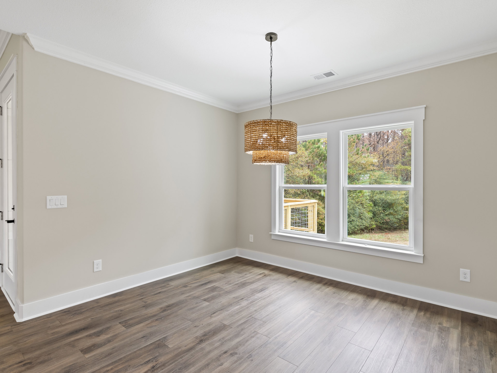 Wood flooring with white trim, white door, chain-hung light fixture, windows framed in wood with wire mesh, trees visible outside