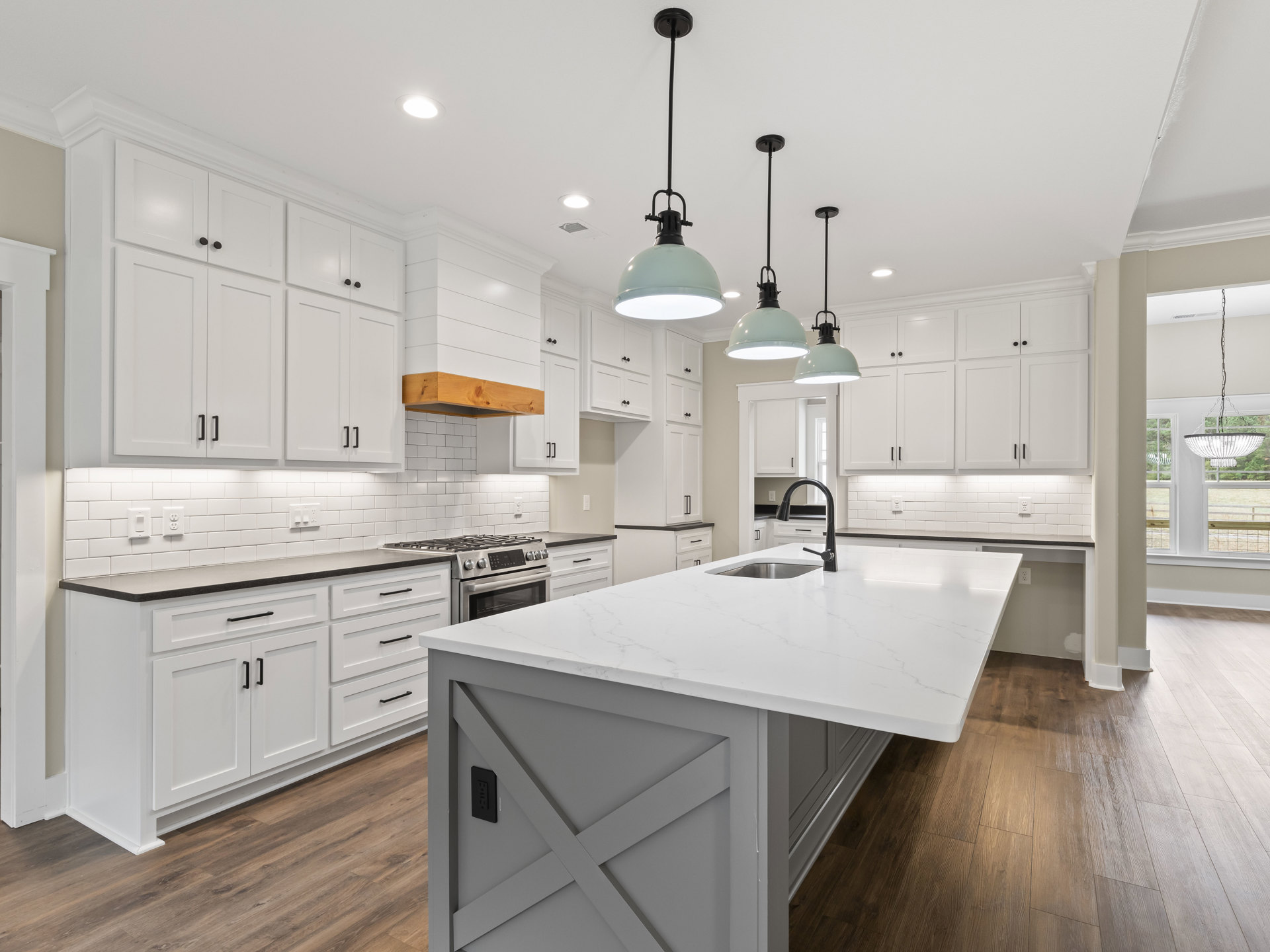 Kitchen with white cabinets and countertops, white island, black ceiling light fixture, white walls, black floor lamp, stainless steel sink, tile flooring, modern appliances