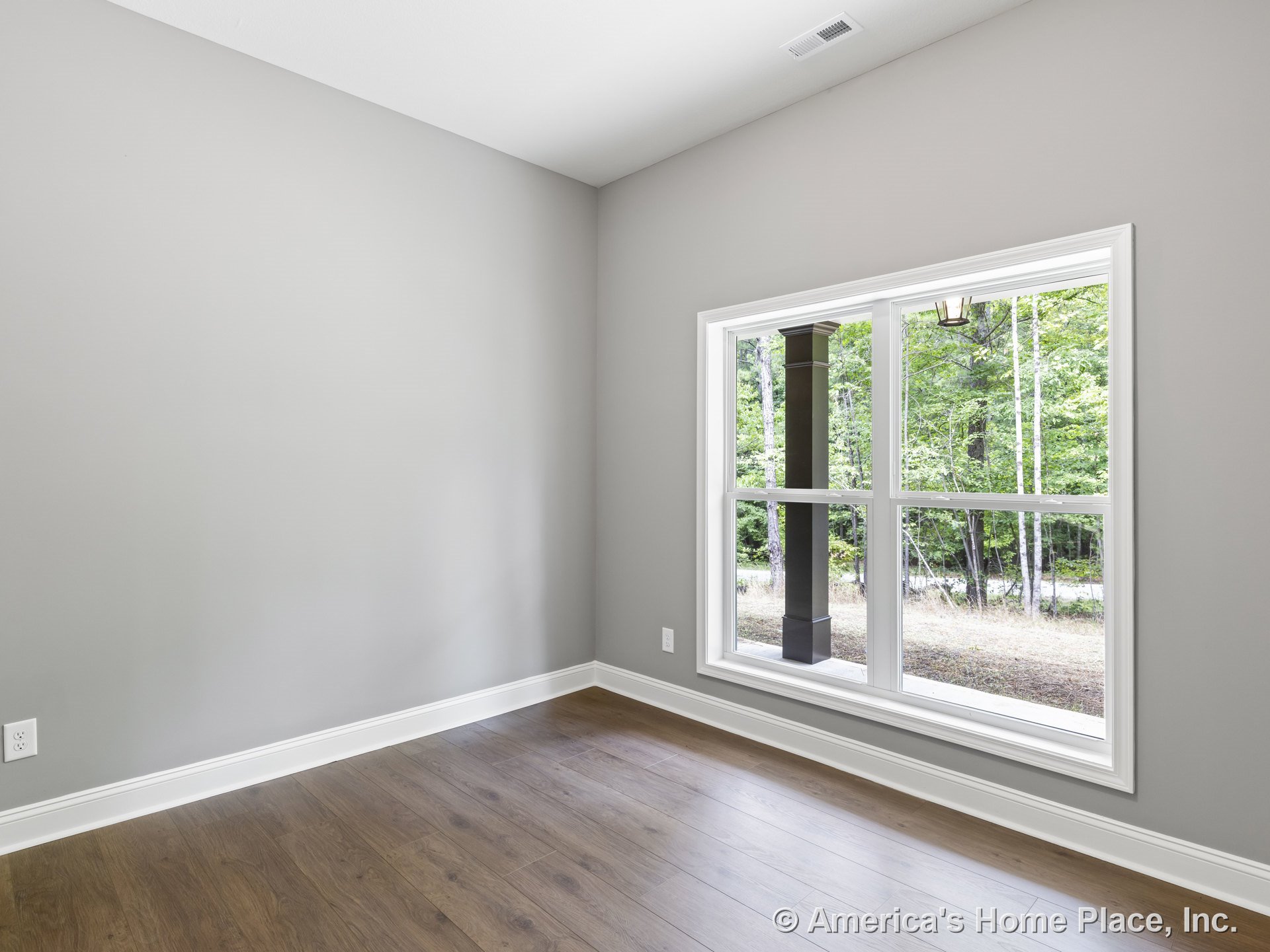 Large double windows with white trim allow natural light into a room with light gray painted walls, wood plank flooring, white baseboards, and a ceiling vent; an outdoor porch