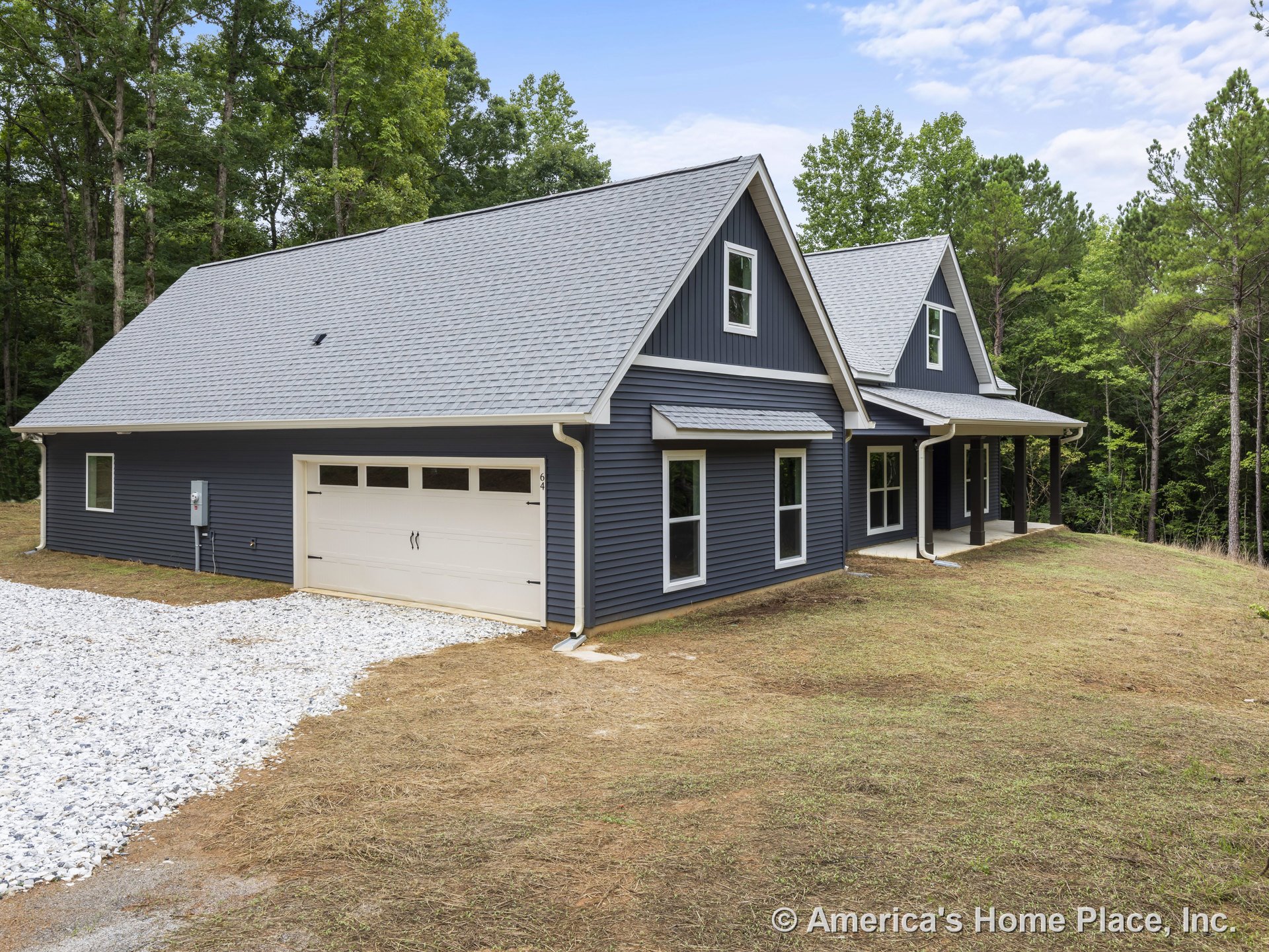 Dark blue vertical siding exterior with covered front porch supported by white columns, two-car garage with white doors, multiple rectangular windows, gray shingle roof, and