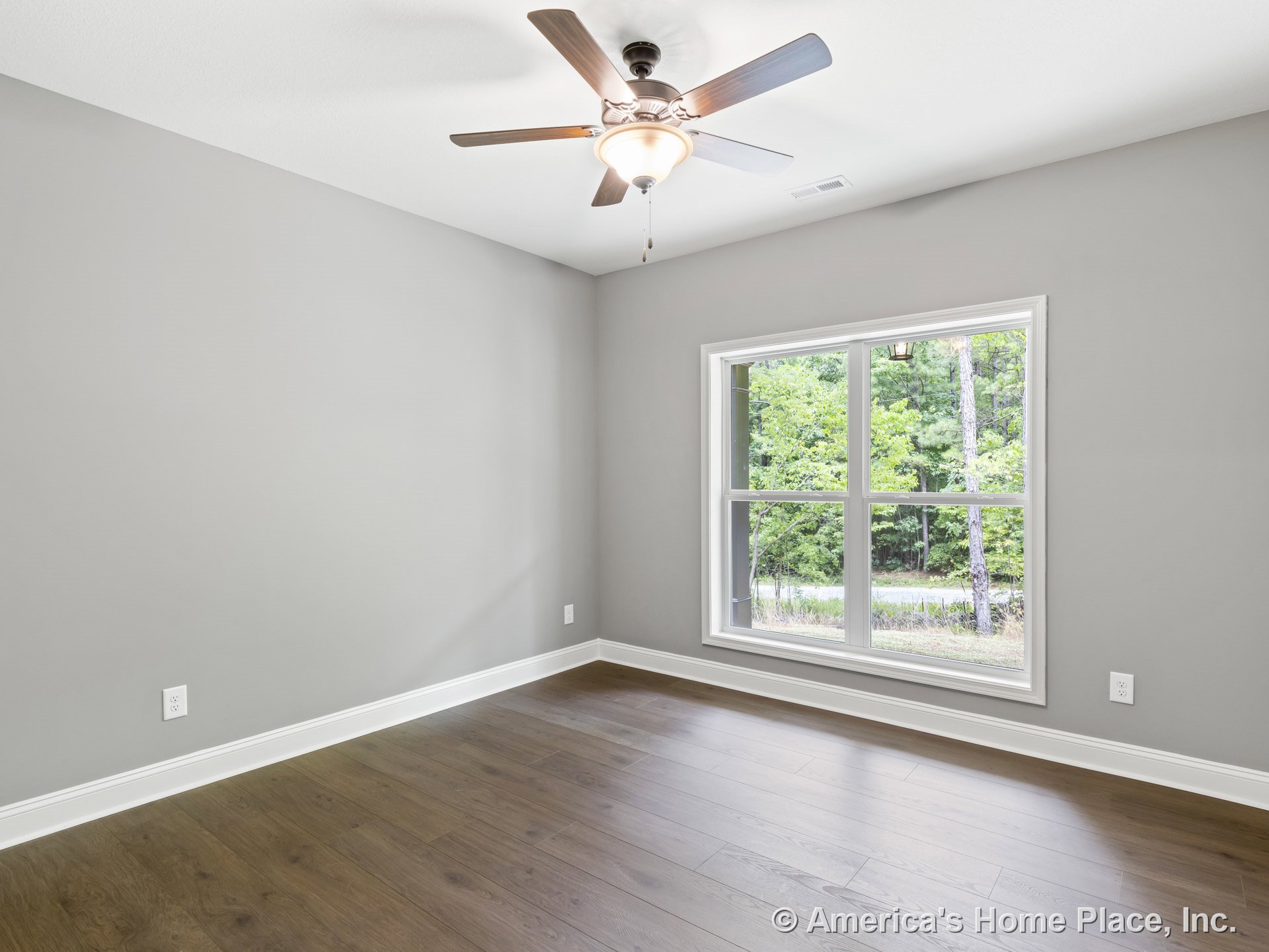 Wide plank wood flooring, large double window with white trim, ceiling fan with built-in light, gray painted walls, white baseboard trim, and smooth white ceiling in an empty