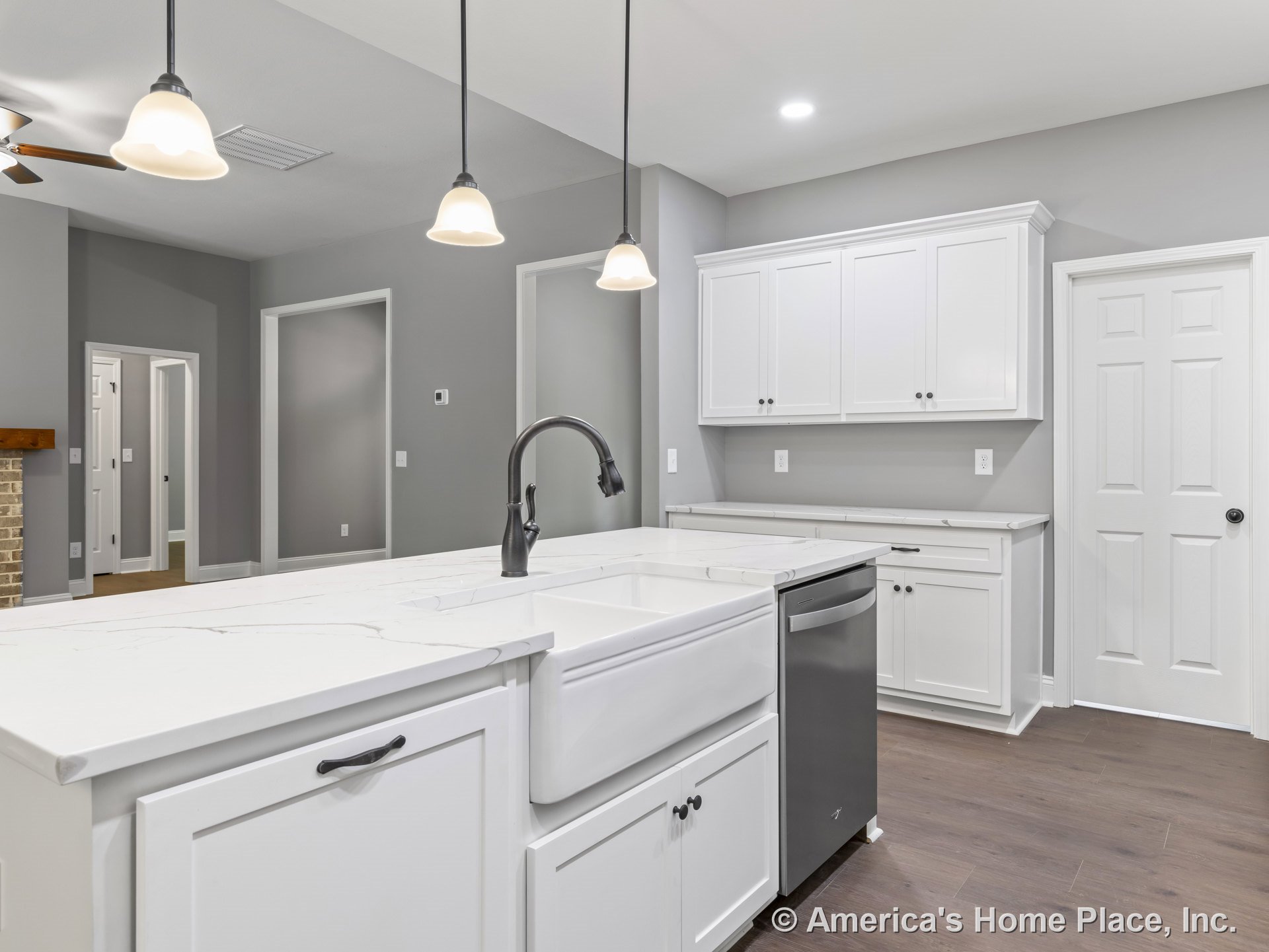 White shaker cabinets with marble-look countertops, farmhouse sink beneath pendant and recessed lighting, gray painted walls, wood flooring, built-in dishwasher, and detailed trim.