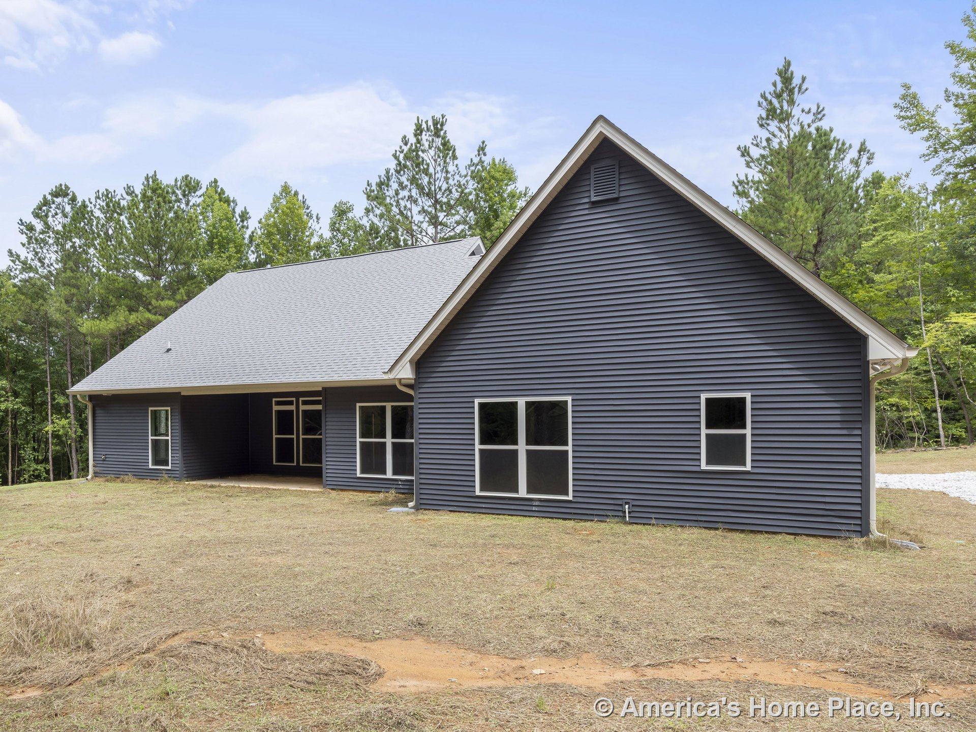 Dark horizontal vinyl siding exterior with white trim, gable shingle roof, multiple large windows, and a covered rear porch on a single-story structure.