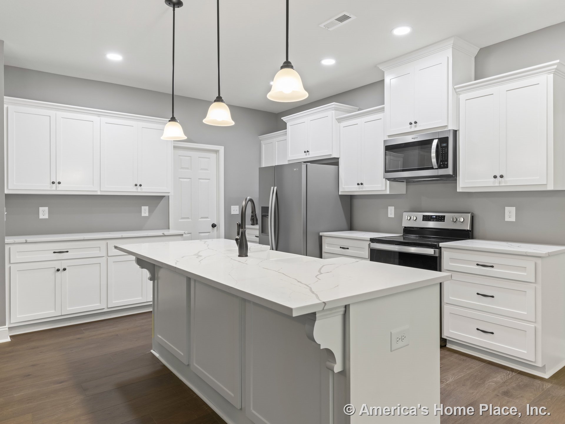 White shaker cabinets and marble-look countertops surround a spacious kitchen island with double sink, stainless steel appliances including built-in microwave and electric range