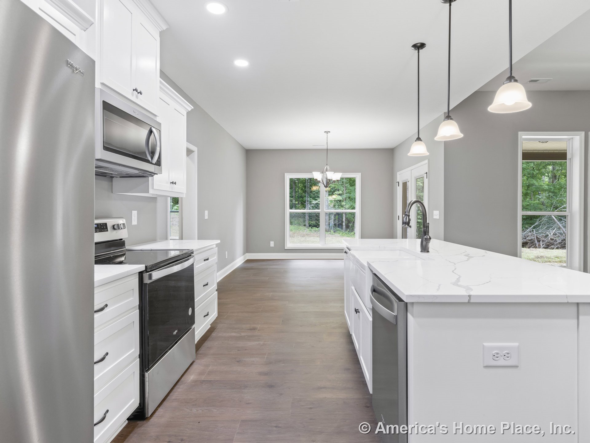 White shaker cabinets and marble-look countertops with stainless steel appliances, pendant lights above the island sink, wood flooring, built-in microwave, electric range, and