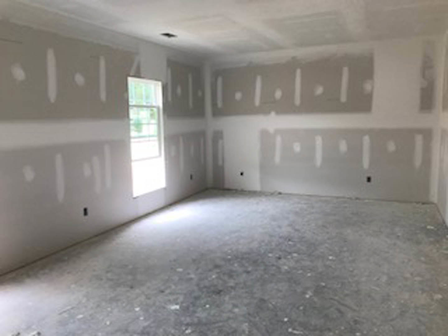 White plaster walls, large window with sunlight illuminating light wood flooring, smooth white ceiling