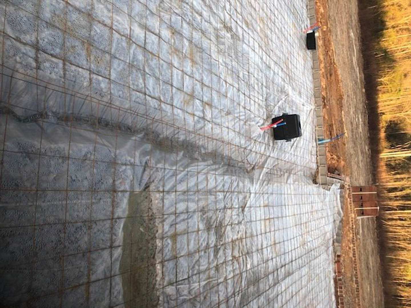 Clear plastic sheeting draped over concrete exterior wall of residential building under construction