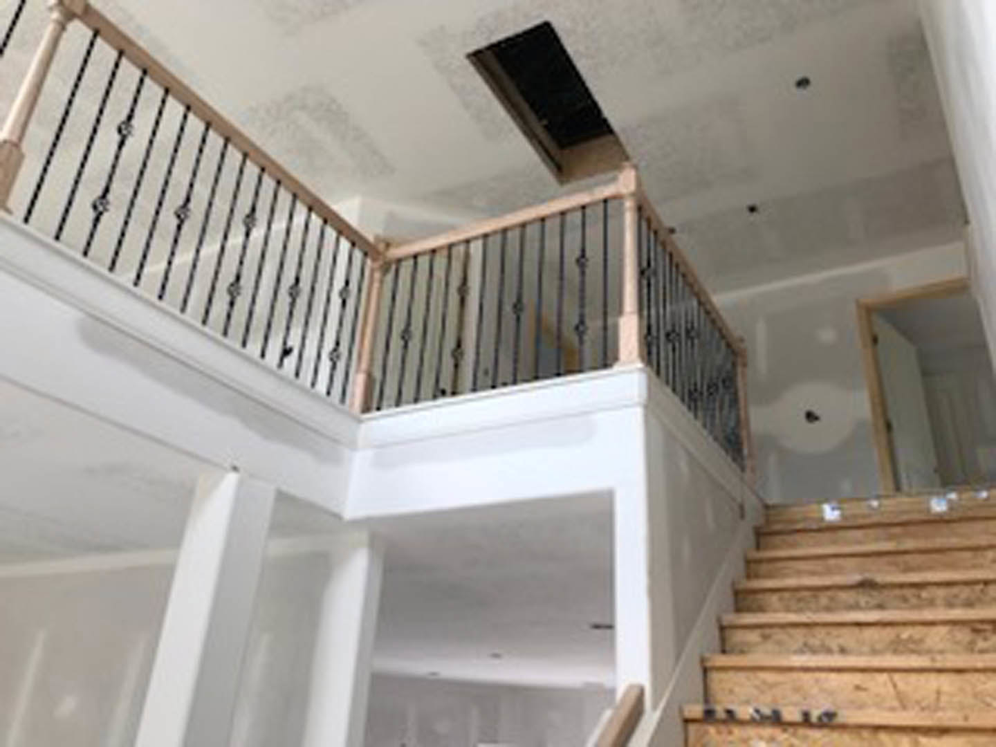 Wood staircase with white balusters and handrail, plaster walls, ceiling vent, and decorative molding in a residential interior