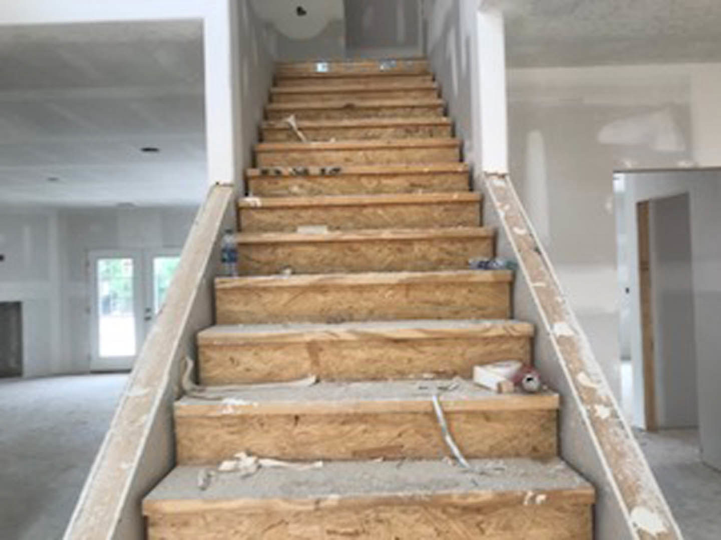 Wood staircase with open risers, white walls, and light hardwood flooring in a modern residential interior