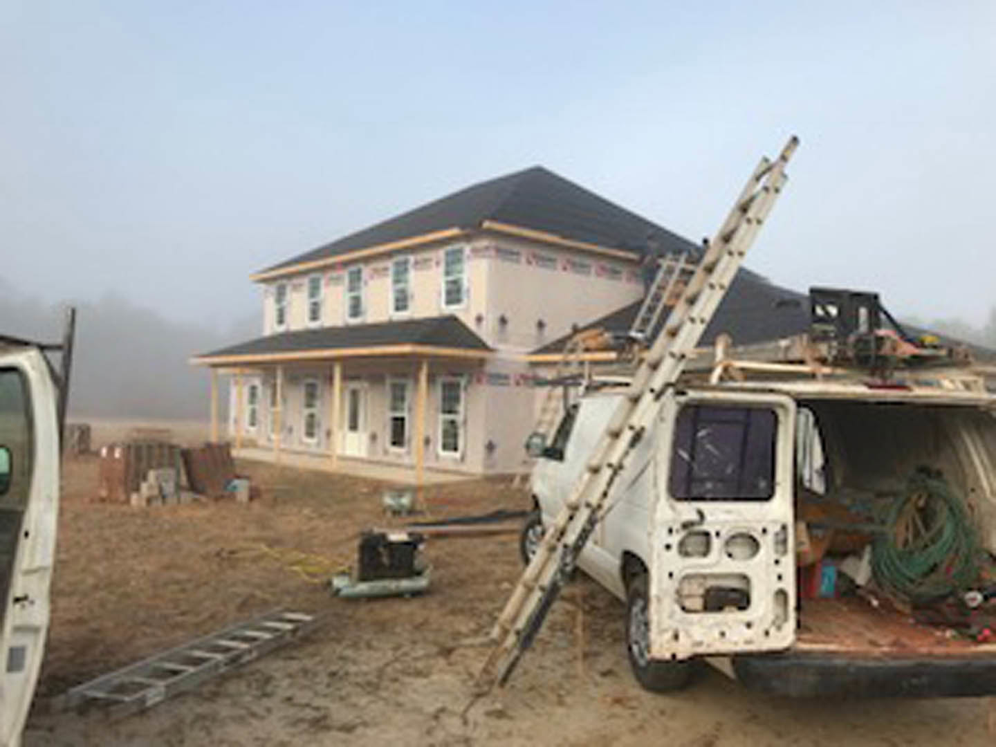 White pickup truck with ladder parked in driveway in front of two-story house with light siding and white trim