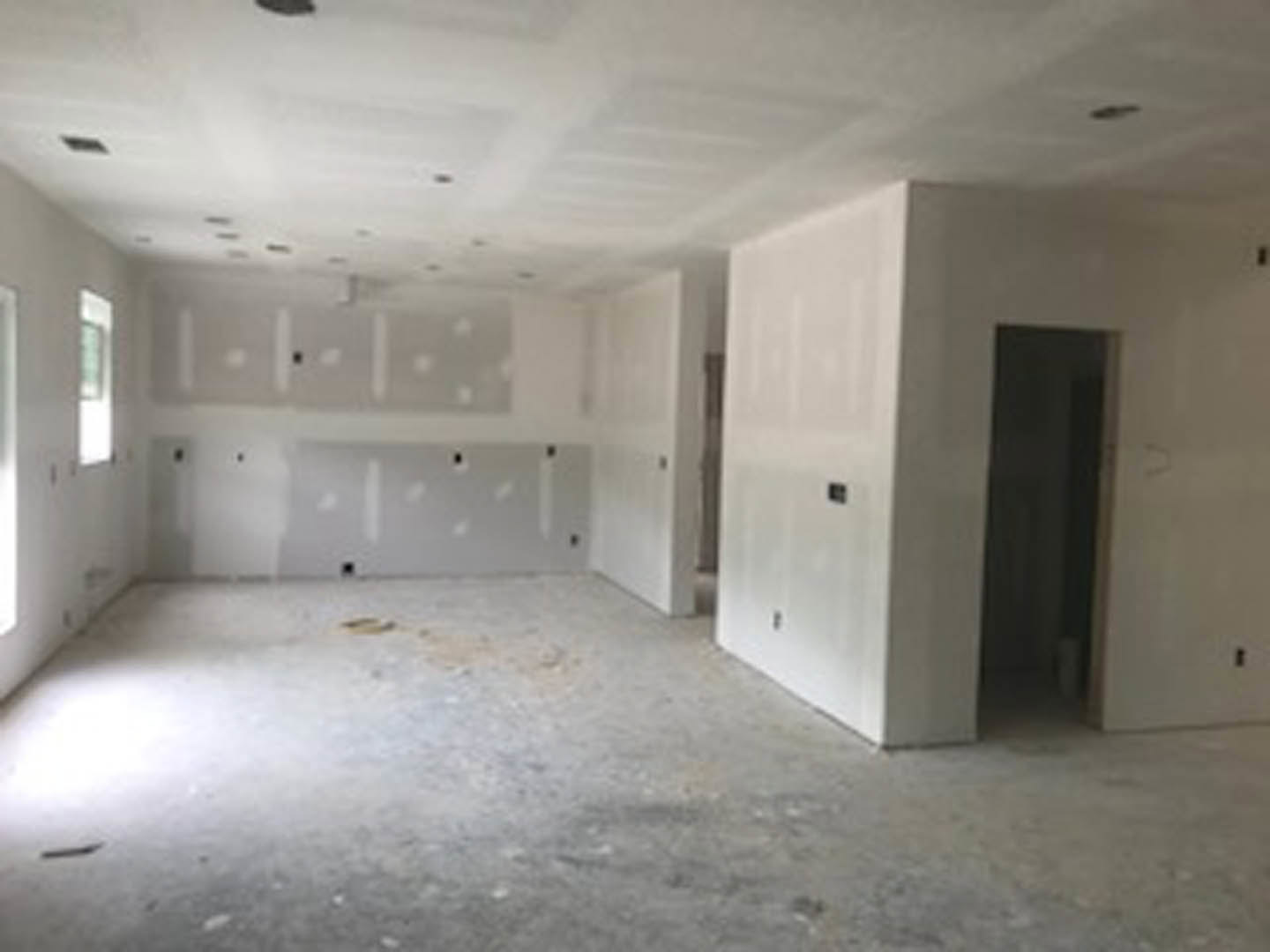 White walls and concrete floor in a minimalist room with a single door, visible ceiling, and neutral finishes.