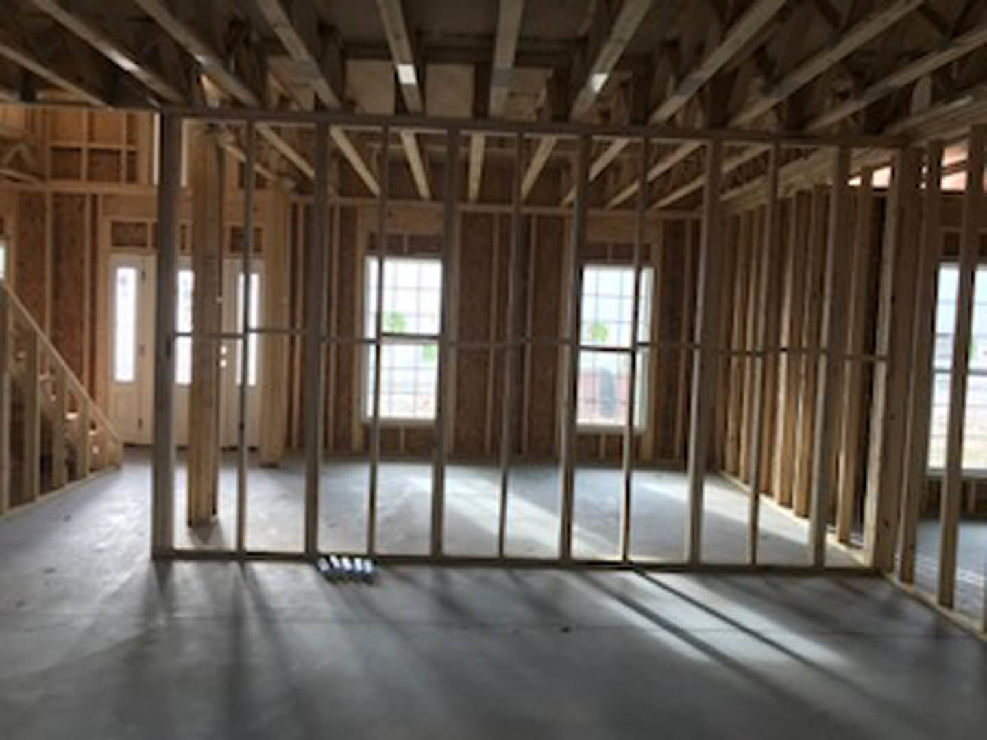 Bright room with large windows, wood plank flooring, exposed ceiling beams, and white walls