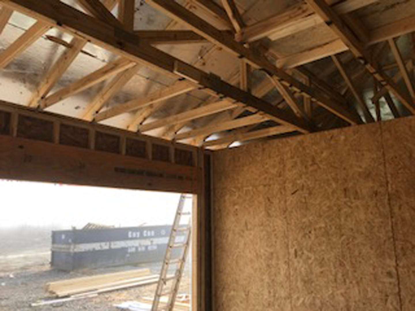 Exposed wooden framing and beams inside a partially constructed residential building, with unfinished walls and visible lumber.