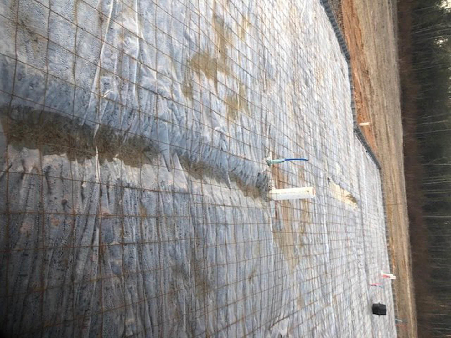 Brick and concrete exterior with composite material fencing, netted fence section, and white tarp visible in foreground