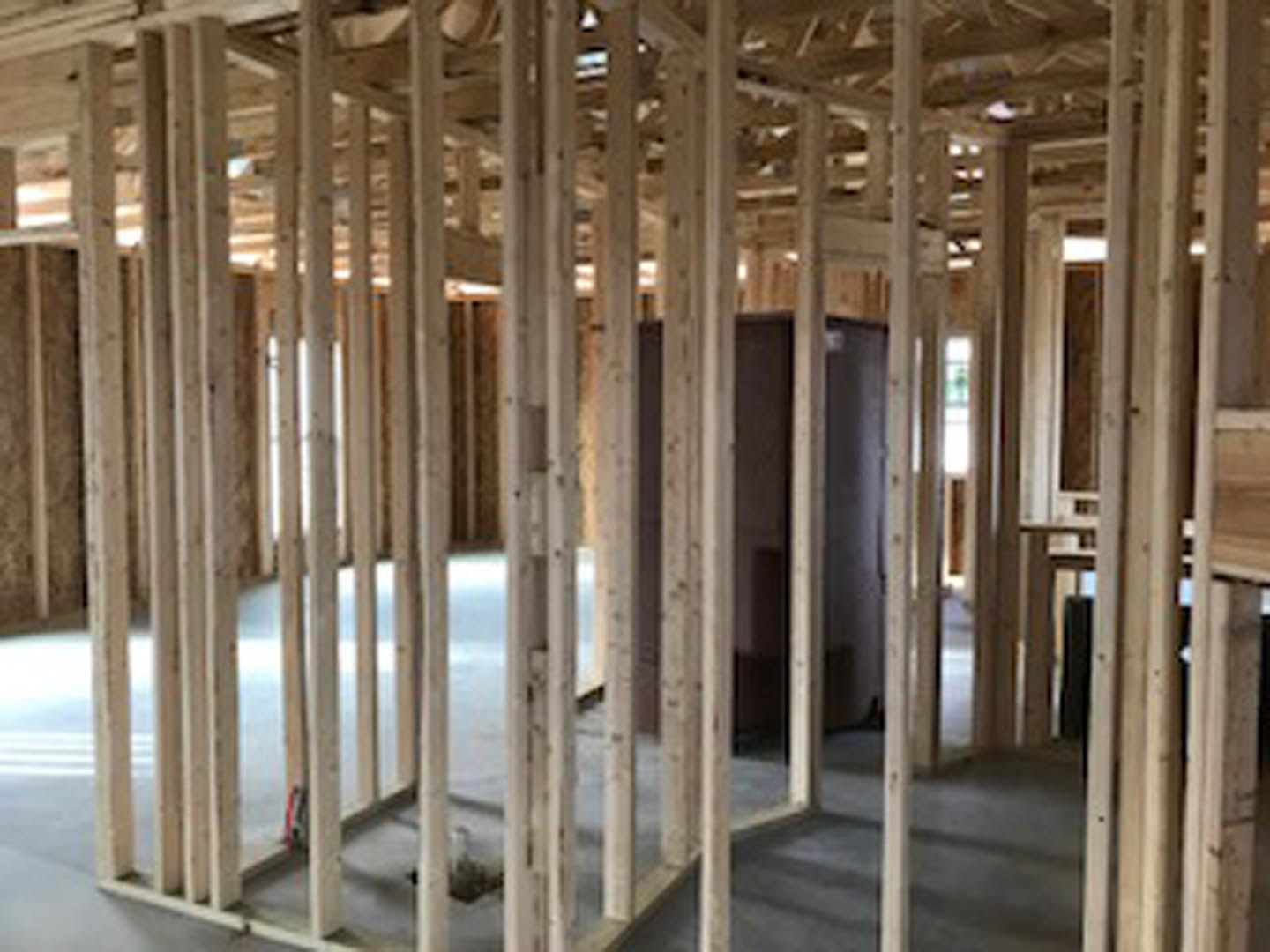 Open room with exposed wood beams, hardwood floor, and large window framed in natural wood