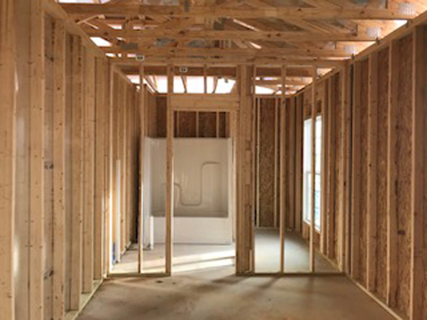Curved glass shower enclosure with chrome fixtures, wood plank ceiling with exposed beams, large window, light-colored tile flooring