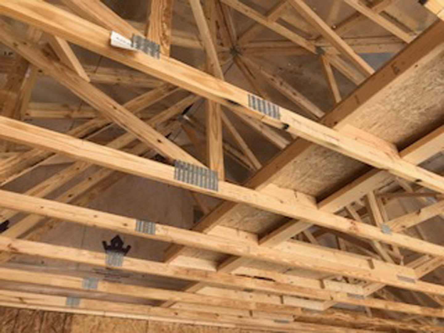 Exposed wooden beams spanning a vaulted ceiling with visible planks and insulation