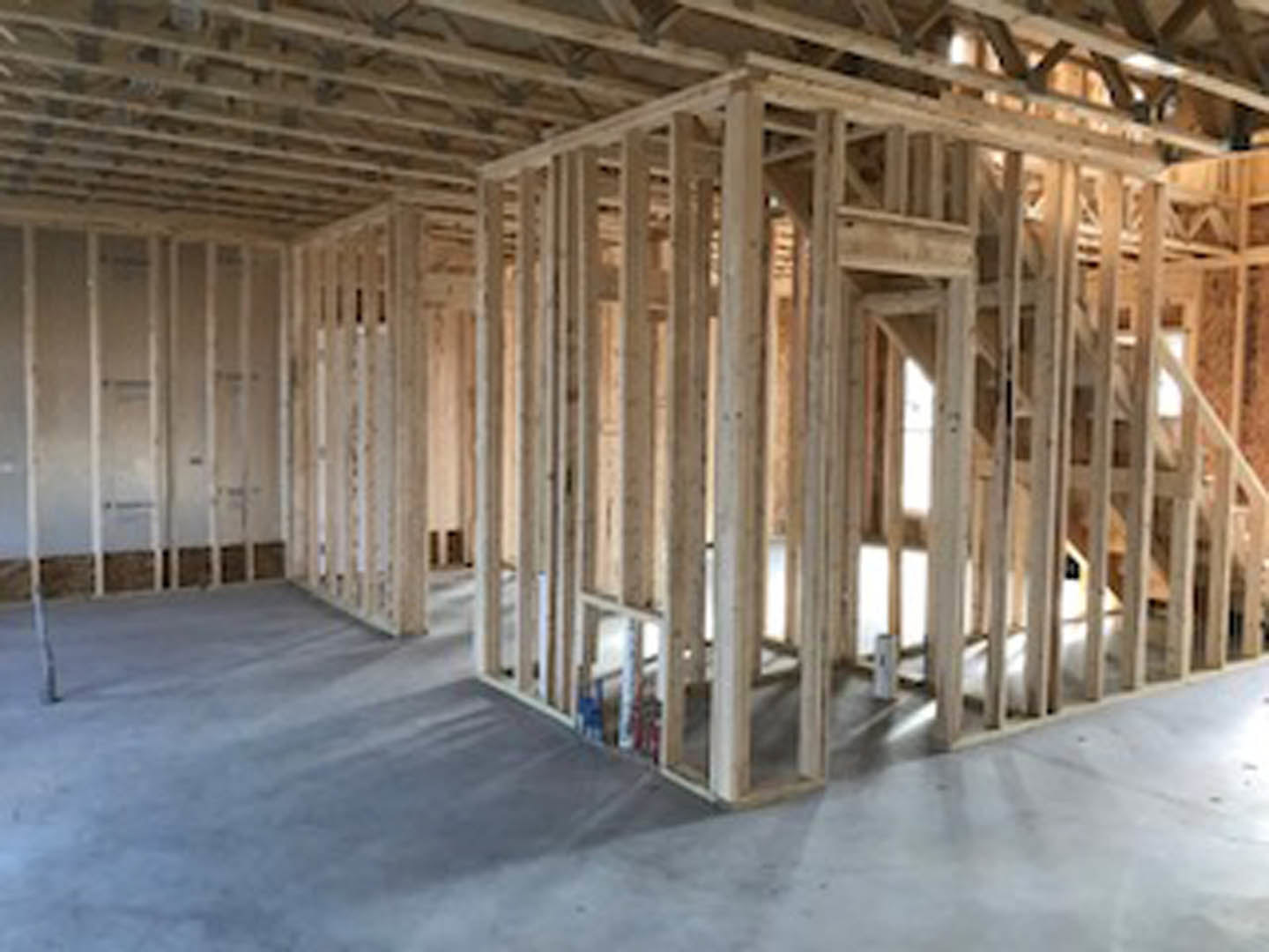 Open room featuring a wall clad in vertical wood planks, exposed ceiling beams, and light hardwood flooring.