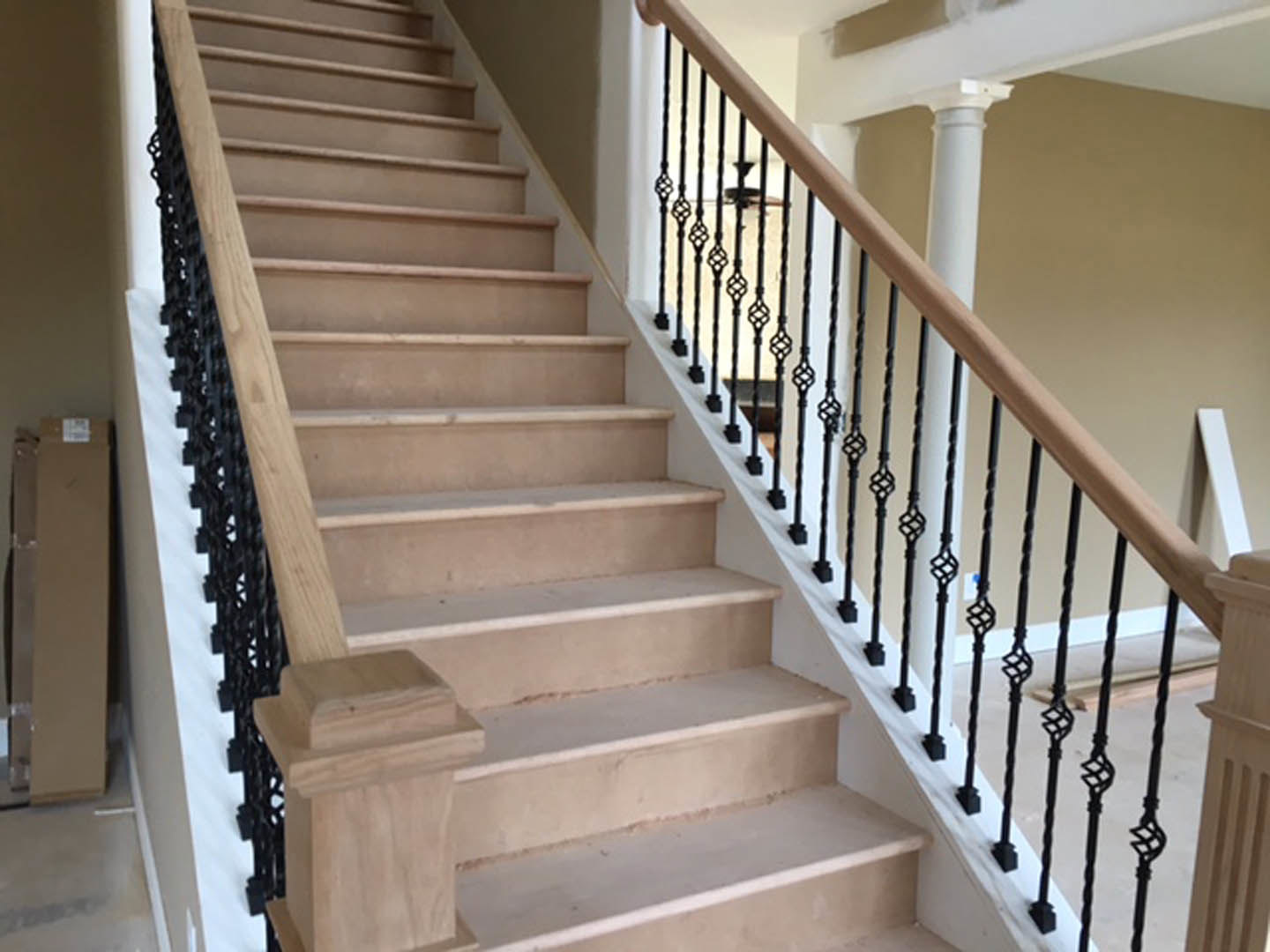 Staircase with black metal railings, wooden post, white pillar, and white shelf in a modern interior