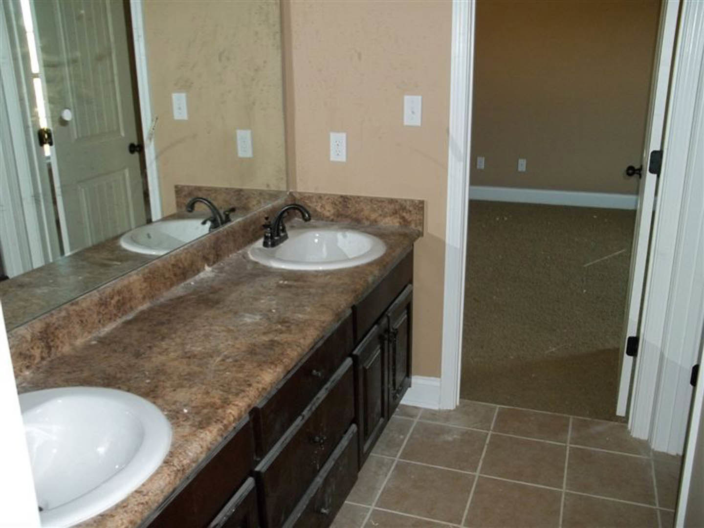 Bathroom with marble countertop, double white sinks, chrome faucets, tile floor, and neutral wall finishes