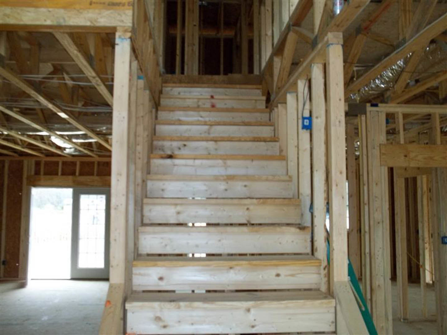 Wooden staircase with hardwood treads and risers, exposed ceiling beams, and plank flooring in a modern interior
