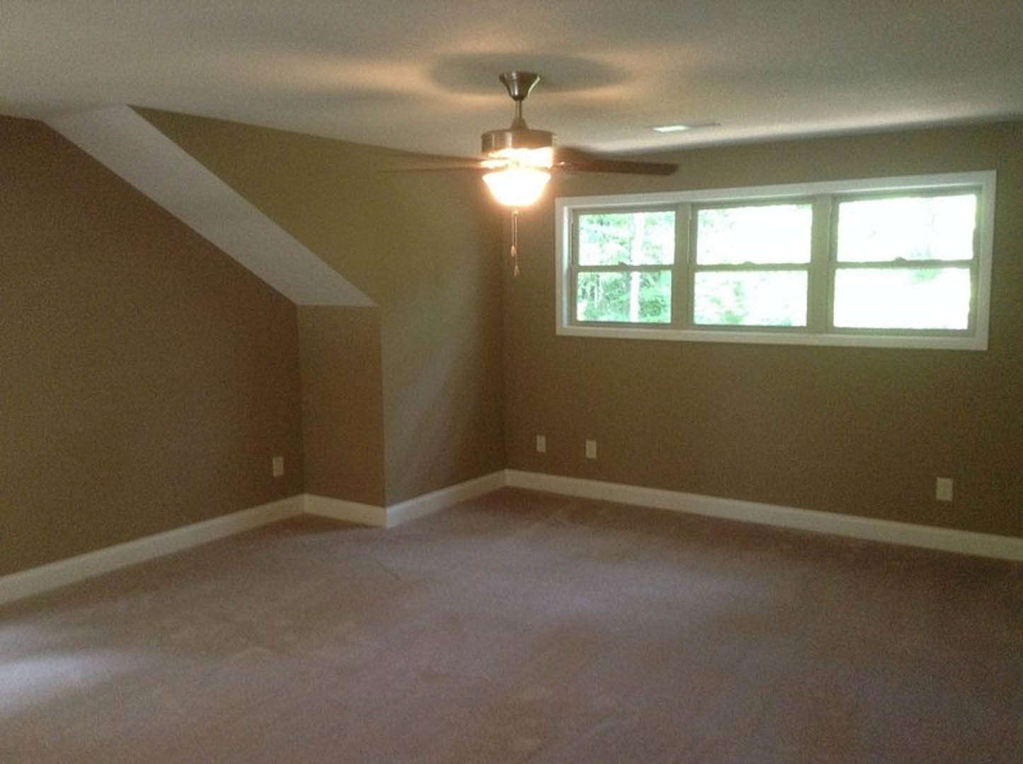 Carpeted room with white walls, ceiling fan, multiple windows framed in white trim, and smooth plaster ceiling