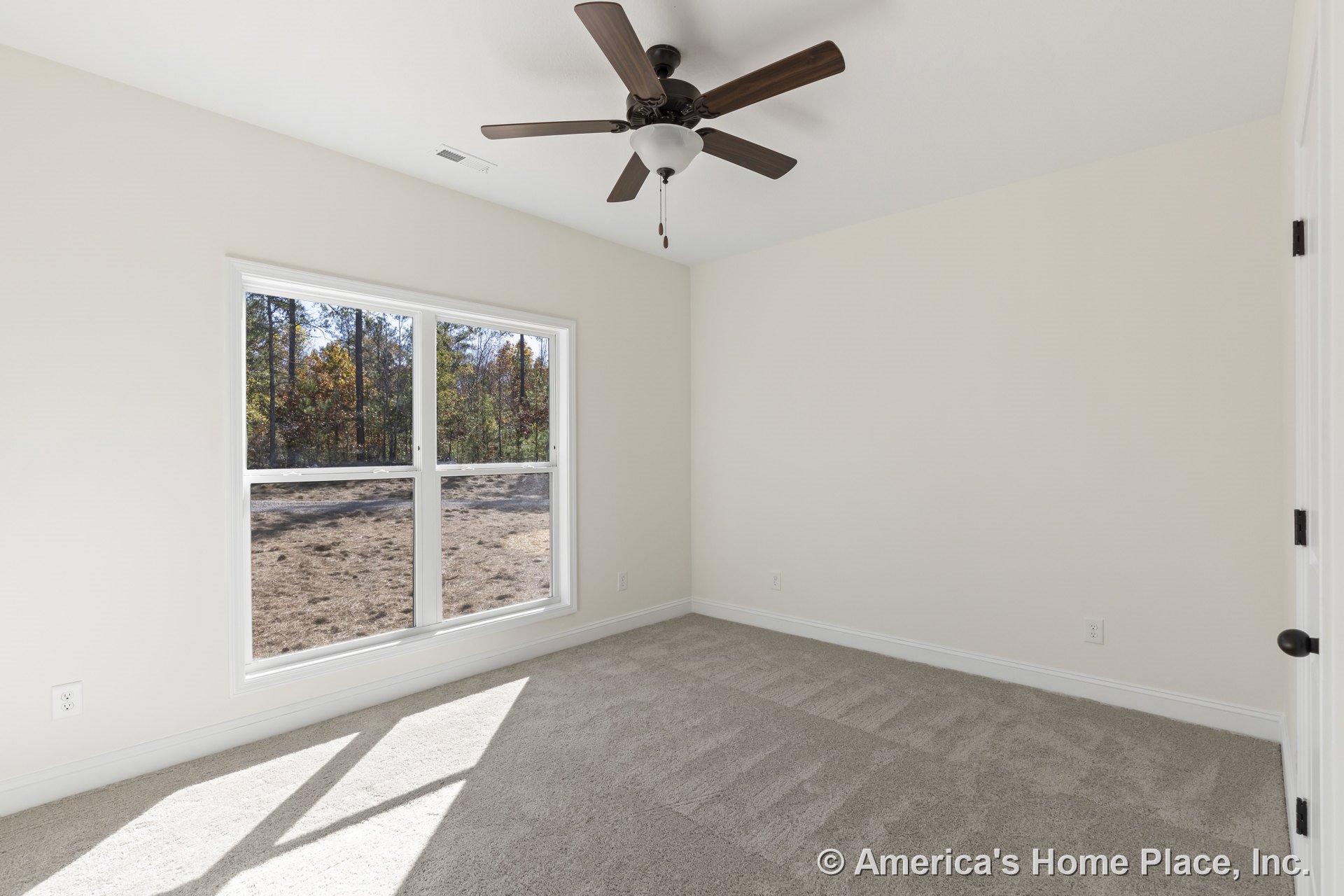 Bedroom with large double window framed in white trim, beige carpet flooring, ceiling fan with integrated light fixture, neutral wall color, white baseboards, and interior door