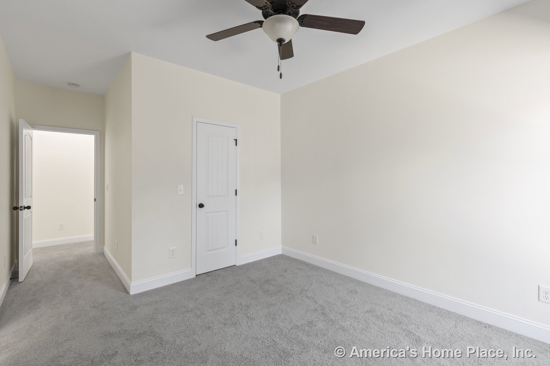 Bedroom with light carpet flooring, ceiling fan and light fixture, white baseboards and trim, paneled closet door, neutral painted walls, interior door featuring dark hardware.