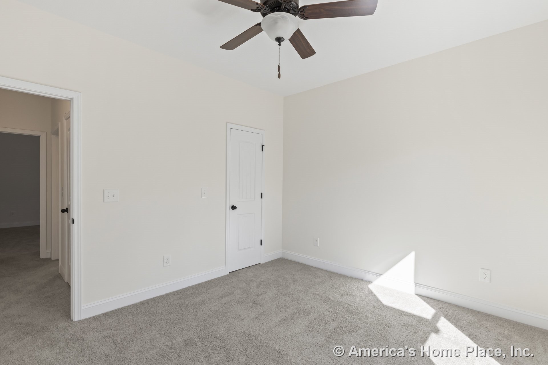Bedroom with light carpet flooring, white baseboards and trim, ceiling fan with dark blades and integrated light fixture, paneled interior door, neutral wall color, window