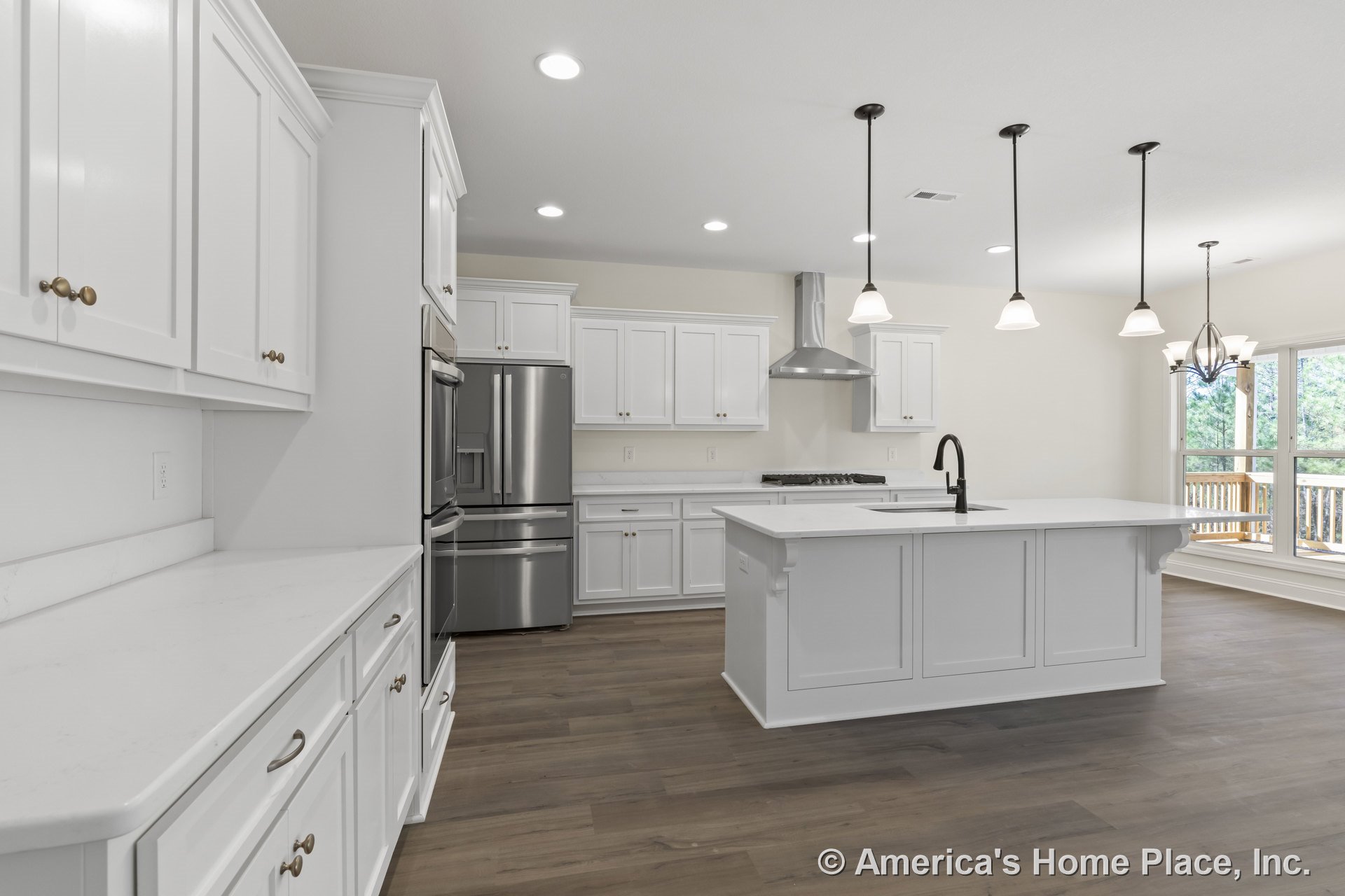 White shaker cabinets and quartz countertops with stainless steel range hood and appliances; pendant lights hang above a central island; wood plank flooring extends into an open