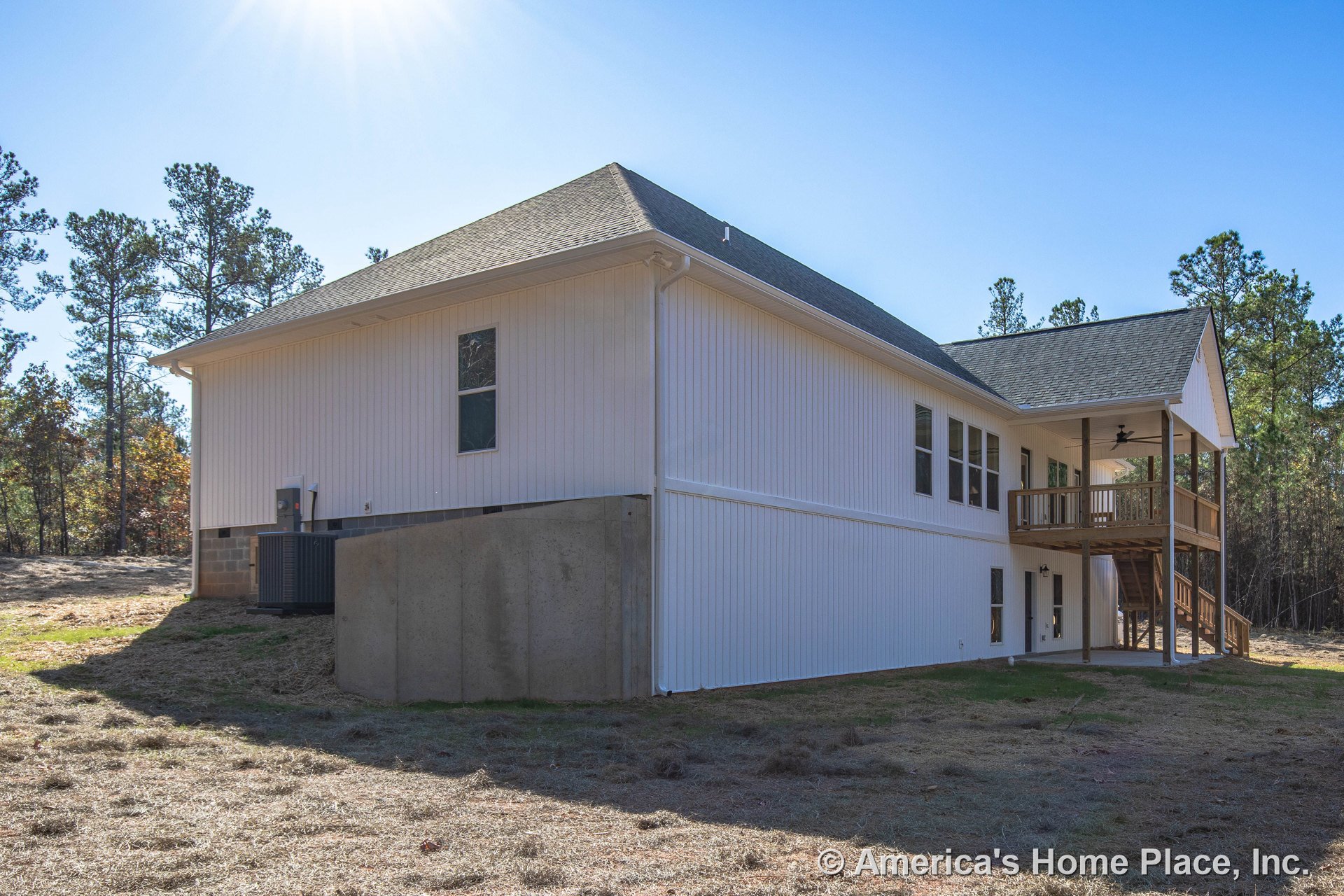 White vertical siding exterior with raised concrete foundation, multiple rectangular windows, covered upper porch featuring wood railings, exterior staircase, contrasting trim